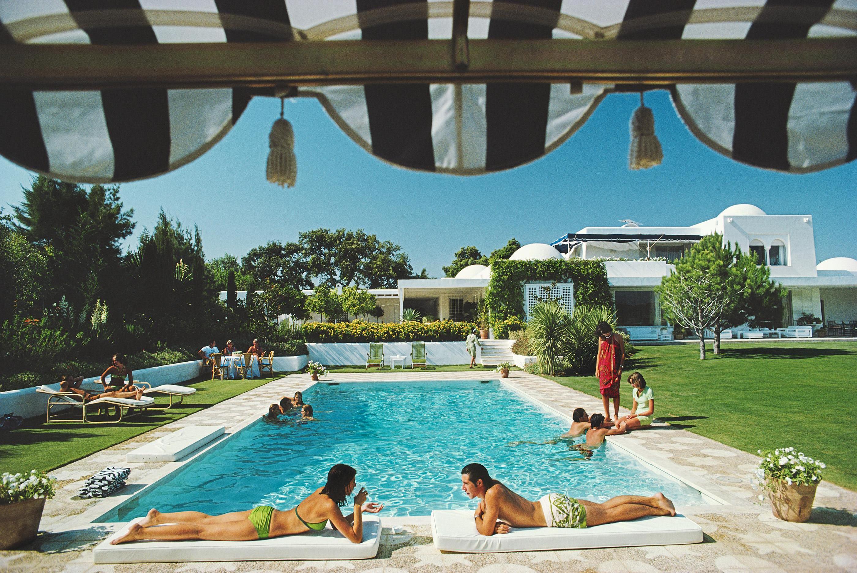 Junto a la piscina en Sotogrande
1975 (impreso posteriormente)
Impresión C
Edición de 150, sellada con tu firma y numerada a mano, con certificado de autenticidad del patrimonio de Slim Aarons. 

Pie de foto: Bañistas alrededor de una piscina en