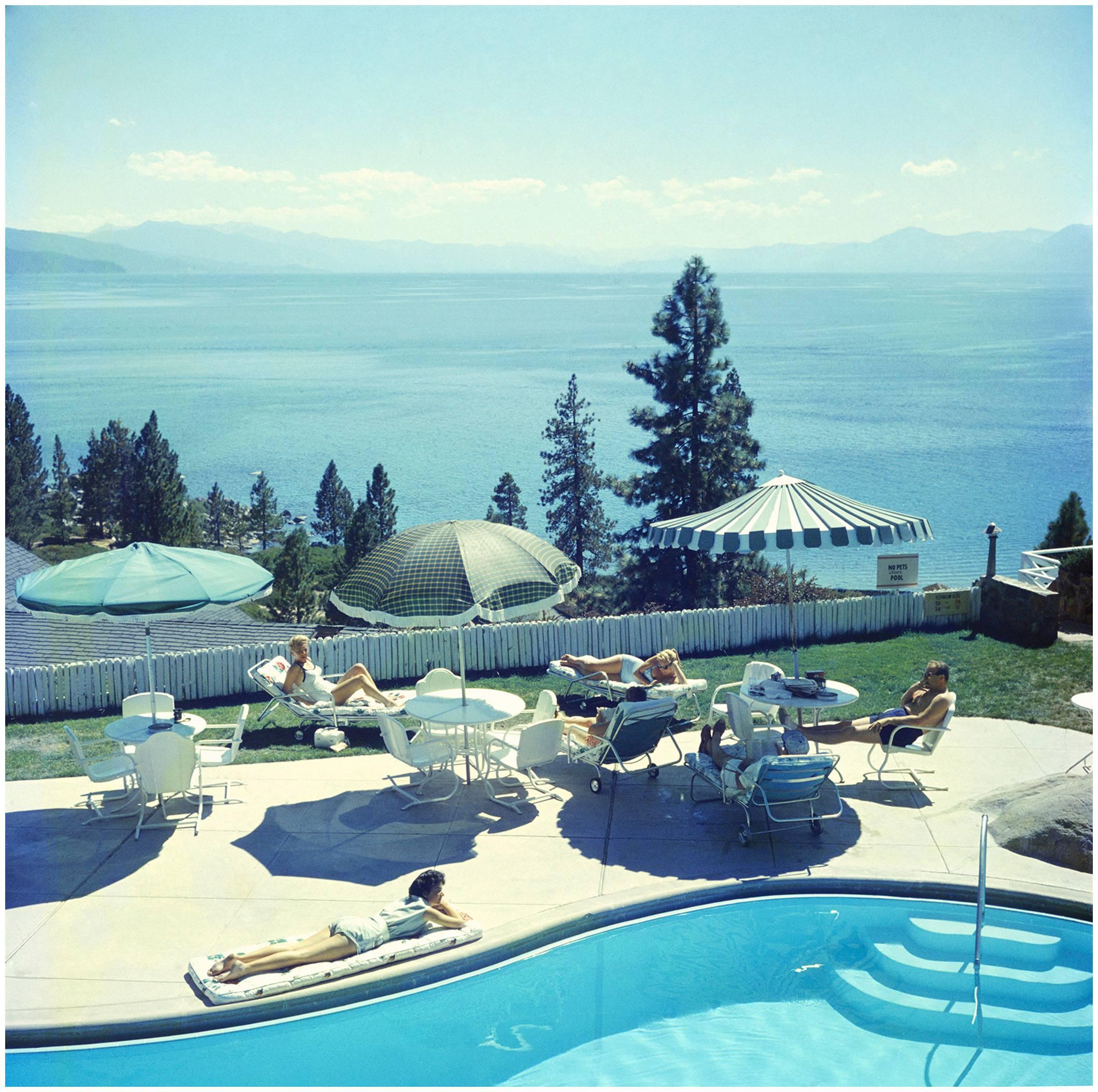 A group of people relaxing by a pool near Lake Tahoe, California, 1959. 

Relaxing at Lake Tahoe
Slim Aarons Estate Edition
48x48 inches
Numbered and stamped by the Slim Aarons Estate. 
Certificate of Authenticity included. 

Purchaser will get the