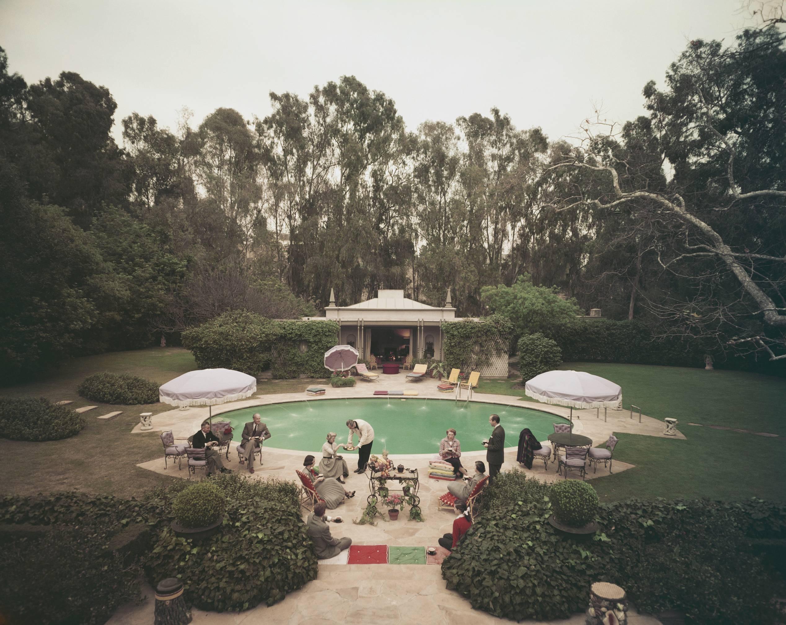 'Scone Madam'  (Slim Aarons Estate Edition)
Afternoon tea round the pool on a cold day at the home of interior decorator James Pendleton in Beverly Hill, 1960. Fashionably smartly dressed guests enjoy afternoon tea served by a butler beside the