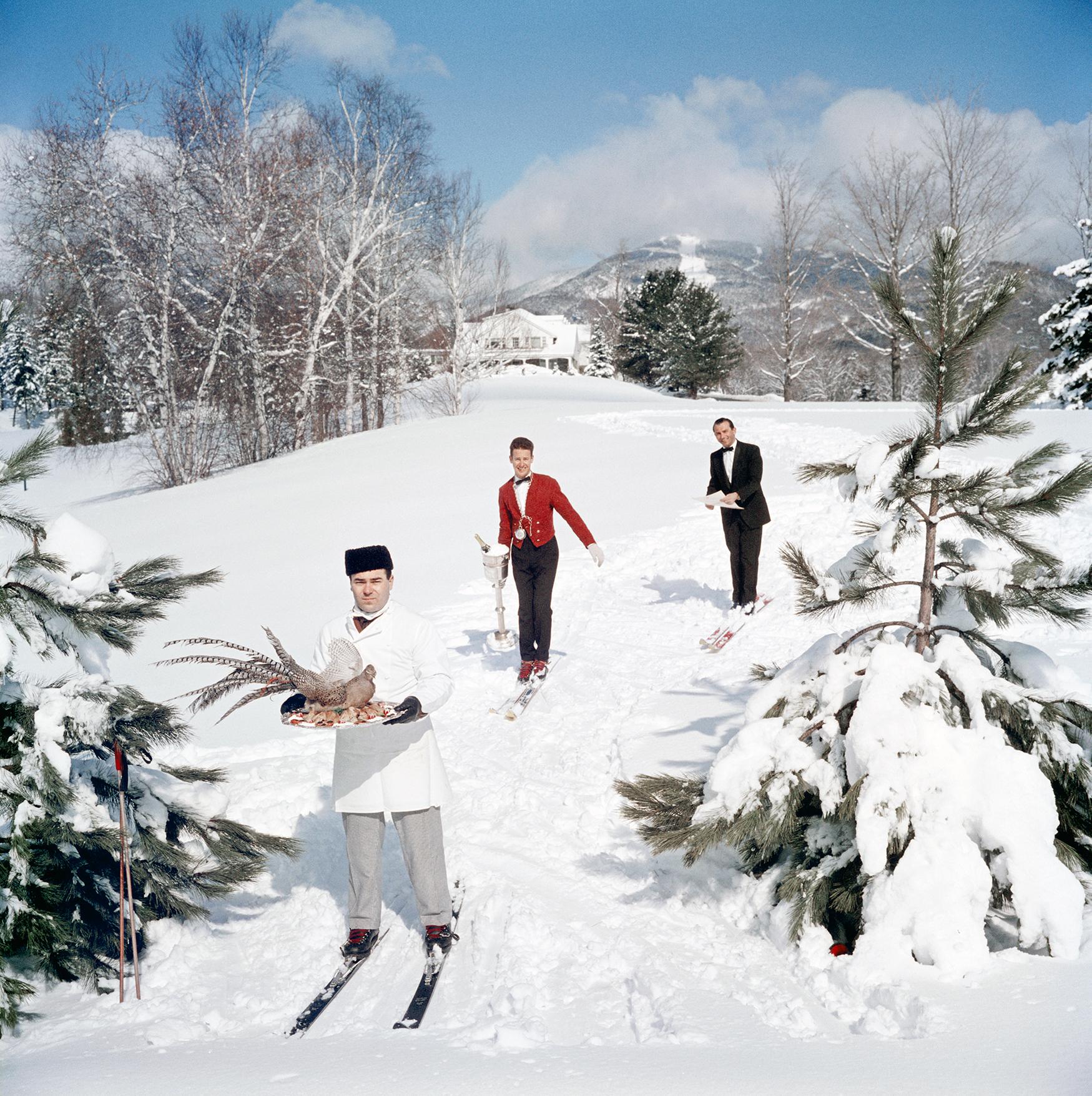 Skiing Waiters
1960
C-Print
Estate signature stamped and hand numbered edition of 150 with certificate of authenticity from the estate.   

Three skiing waiters on a ski slope, with the man in the foreground carrying a bird on a tray, the second man