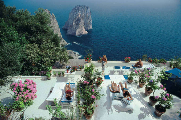 Sunbathers lounge on the white-painted terrace of Il Canille, built into the rocks of Pizzolungo overlooking the waters off the coast of the island of Capri, Italy, in August, 1980. Il Canille is the villa owned by Italian tailor and fashion