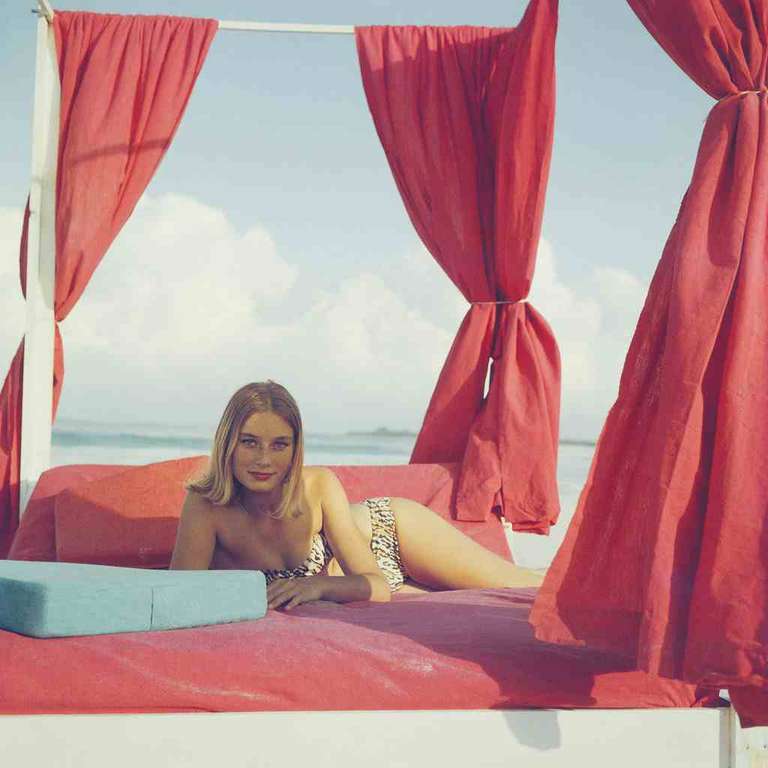 1961: La actriz Tania Mallet se relaja en un póster de cuatro cortinas rojas en Eleuthera, en las Bahamas. Es más conocida por su papel de la desafortunada Tilly Masterson en la película de Bond "Goldfinger".
