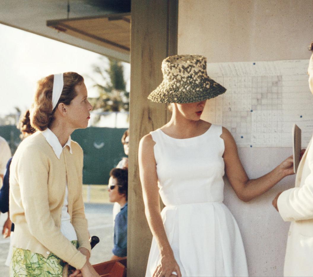 1957—Two women stand talking to a man on the edge of a tennis court in the Bahamas. Behind the main group stand a second group of people talking.

Slim Aarons
Tennis in the Bahamas, 1958
Slim Aarons Estate Edition, Certificate of Authenticity