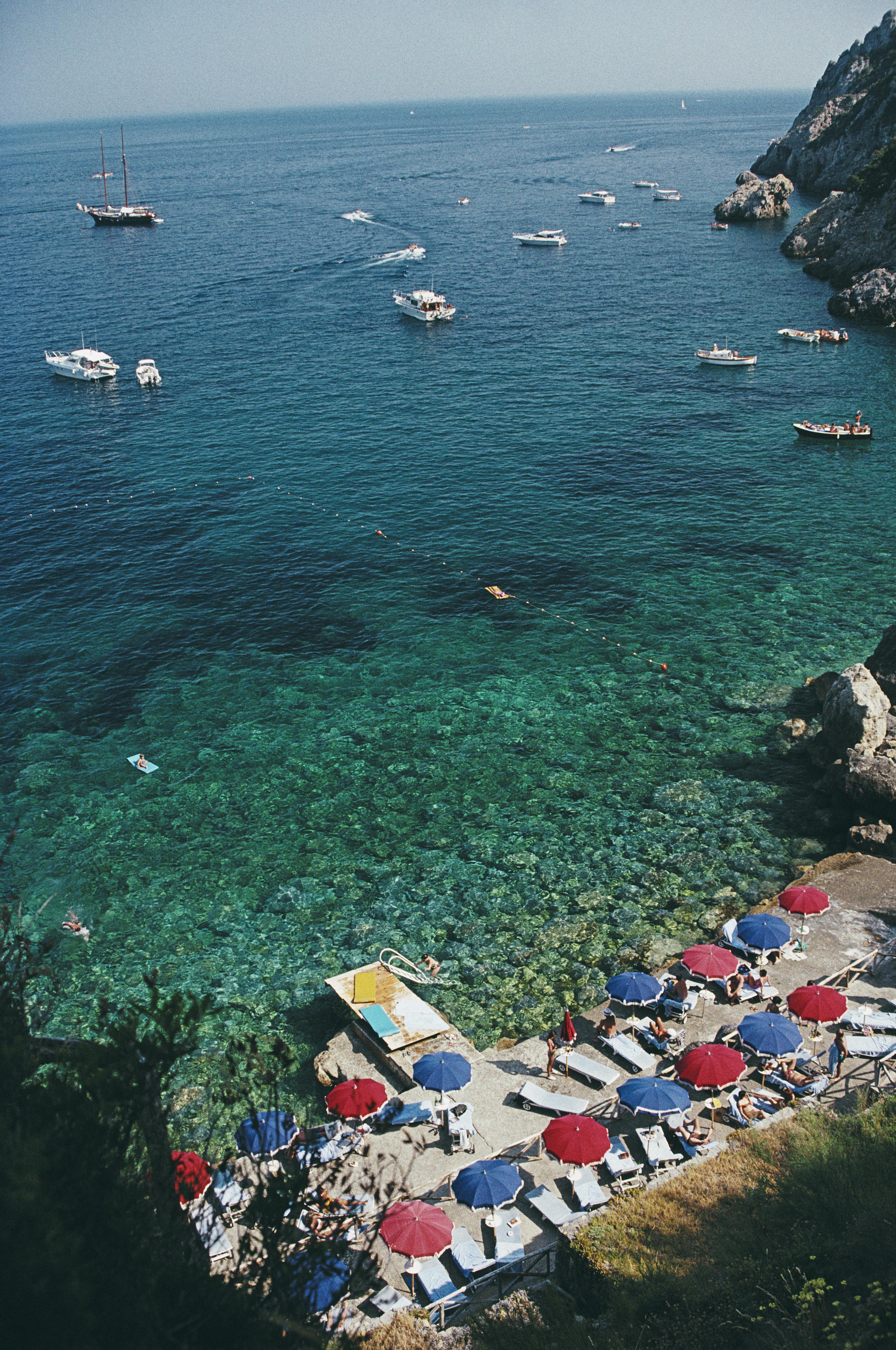 Vue aérienne avec des baigneurs et des parasols et, parsemées de yachts et de petits bateaux, les eaux au large de la côte de Porto Ercole, en Toscane, en juillet 1991. L'image a été prise à l'hôtel Il Pellicano.

Slim Aarons
Piscine Il Pellicano,