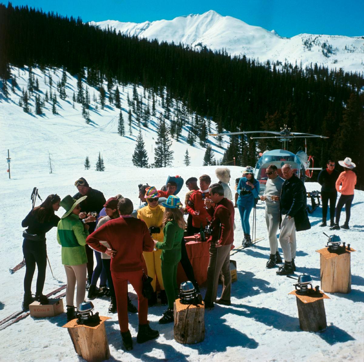 Snowmass Picnic (1967) Limitierter Nachlass gestempelt 

(Foto: Slim Aarons) 

Ein Fonduepicknick im Stehen für modebewusste Skifahrer in Snowmass-at-Aspen, Colorado, mit mehr als fünfzig Meilen Pisten und Schneefeldern. 

Helikopter im Hintergrund.