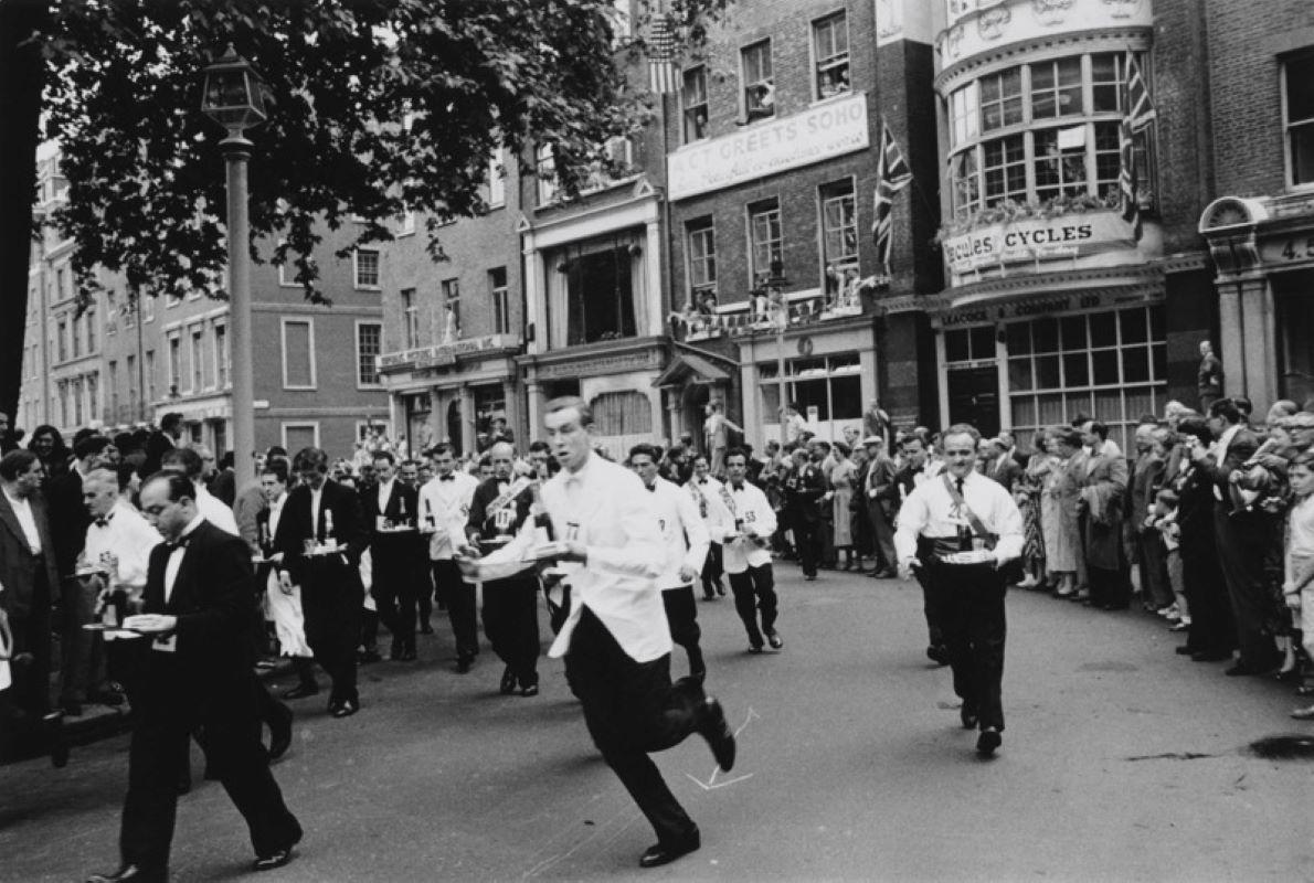 Slim Aarons Black and White Photograph - Soho Waiters' Race (1955) - Silver Gelatin Fibre Print - Limited Estate Stamped