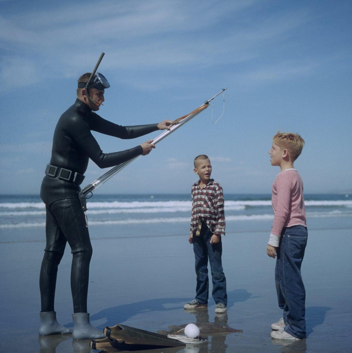 'Speerfischen in San Diego' 1956 Slim Aarons Limitierte Nachlassausgabe

Ein Speerfischer mit Maske, Schnorchel und Neoprenanzug mit zwei Jungen an einem Strand in San Diego, Kalifornien, Oktober 1956. 

Hergestellt aus der