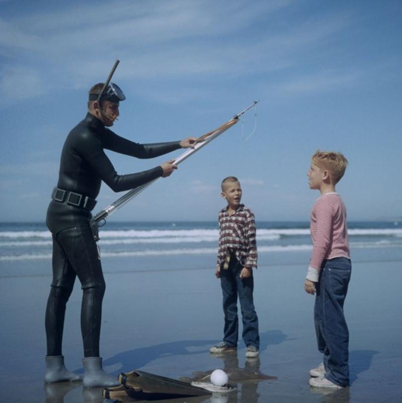 Spear Fishing In San Diego 
1956
by Slim Aarons

Slim Aarons Limited Estate Edition

A spear fisherman in a mask, snorkel and wetsuit, with two boys on a beach in San Diego, California, October 1956.

unframed
c type
printed 2023
20 x 20"  - paper