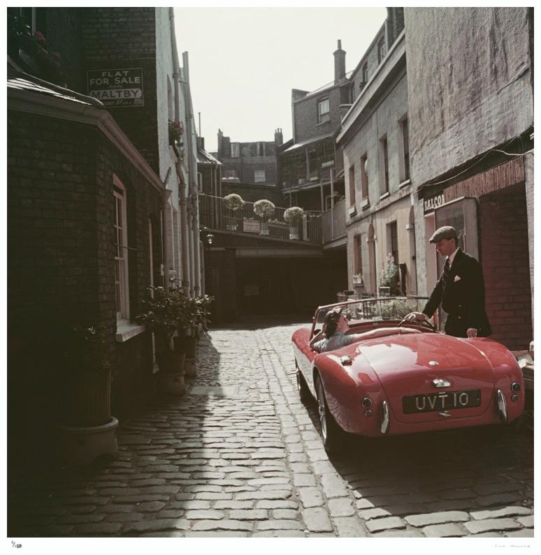 Sportwagen-Couple 1955 Slim Aarons Nachlass-Ausgabe 

John Bryant mit seinem AC-Sportwagen in Kinnerton Place, London SW1. Seine Beifahrerin ist Margaret McAulay. Ca. 1955.

Hergestellt aus der Originalfolie
Mitgeliefertes Echtheitszertifikat