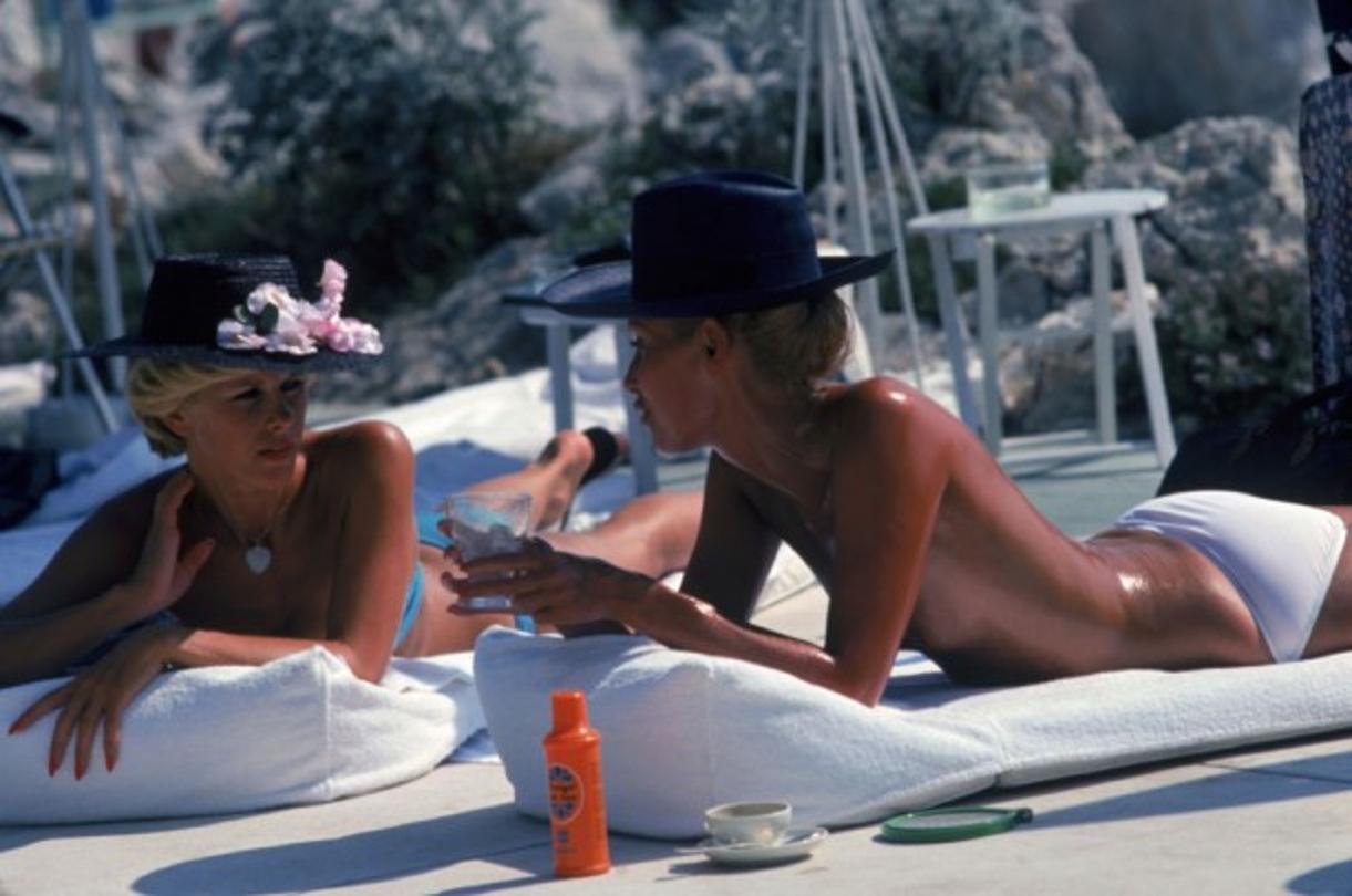 Sunbathing In Antibes 
1976
by Slim Aarons

Slim Aarons Limited Estate Edition

Dani Geneux (left) and Marie-Eugenie Gaudfrin sunbathing at the Hotel du Cap Eden-Roc, Antibes, France, August 1976.

unframed
c type print
printed 2023
16 x 20" - paper