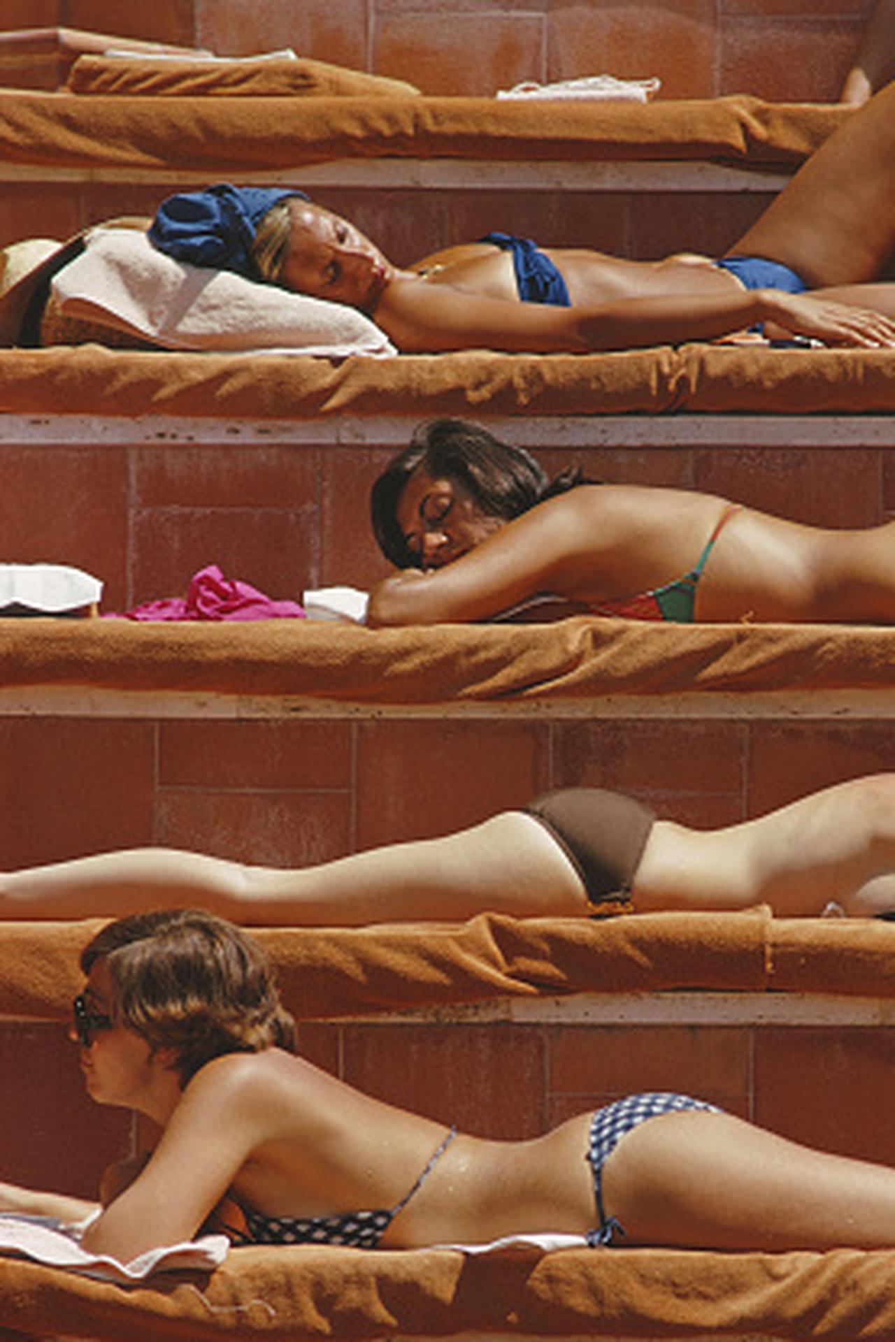 This late 1970s portrait photograph, captured by society photographer Slim Aarons, features sunbathers by a swimming pool at the Hotel Punta Tragara on the island of Capri, Italy, August 1974.

This is an estate stamped and hand numbered edition of