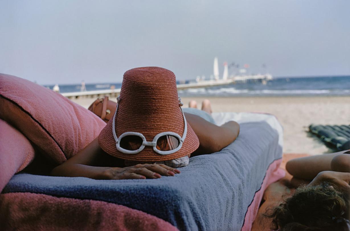 Sunbathing in Venice

A woman sunbathes wearing a novelty straw sun hat with built-in sunglasses, Venice, 1954. 

In this delightfully whimsical photograph by Slim Aarons, taken in 1954, we are offered a glimpse into the fashionable beach culture of