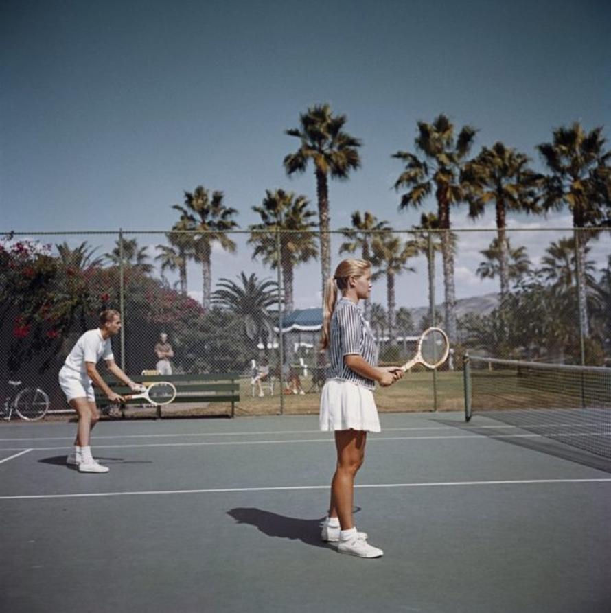 Tennis in San Diego 
1956
by Slim Aarons

Slim Aarons Limited Estate Edition

A man and a woman playing tennis on a court surrounded by palm trees, San Diego, California, October 1956.

unframed
c type print
printed 2023
16×16 inches - paper