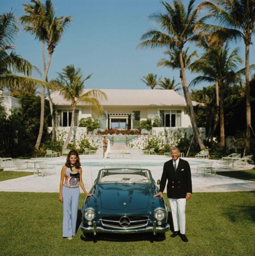 The Fullers 

1970 

May 1970: Alvin and Lilly Fuller outside their new home in Palm Beach, Florida, pose with their fashionable European sports car, the Mercedes 190SL.

Photo by Slim Aarons

20x20” / 51 x 51 cm - paper size 
Archival pigment