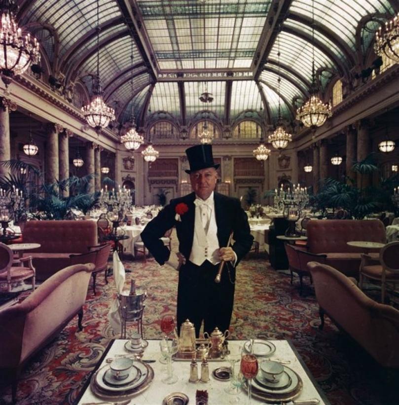 Top People’s Eatery 
1960
by Slim Aarons

Slim Aarons Limited Estate Edition

Journalist Lucius Beebe beside a gold place setting in the glass roofed Garden Court of the Palace Hotel, San Francisco. His walking stick once belonged to a Wells Fargo