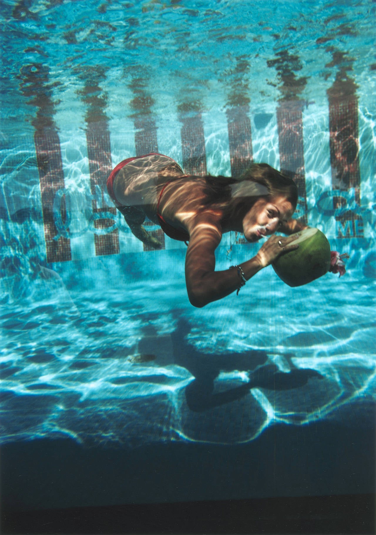 Eine Frau trinkt aus einer Kokosnuss unter Wasser im Pool des Hotels Las Brisas in Acapulco, Mexiko, Februar 1972. 

Nachlassgestempelte und handnummerierte Auflage von 150 Stück mit Echtheitszertifikat des Slim Aarons Estate. 

Slim Aarons
