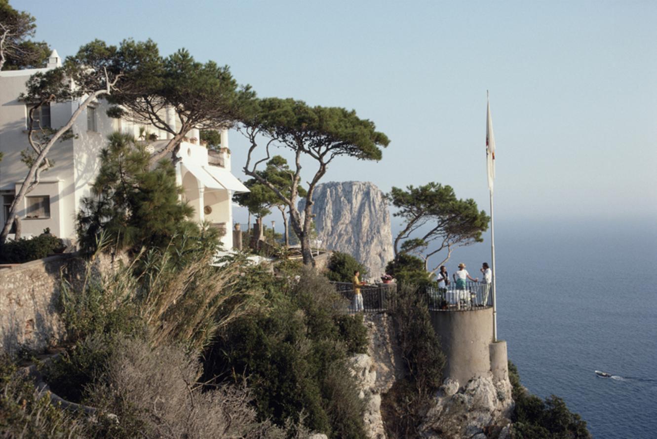 Unghia Marina 
1989
von Slim Aarons

Slim Aarons Limited Estate Edition

Eine Gruppe von Menschen steht auf einer Terrasse in der Unghia Marina auf der Insel Capri, Italien, im September 1989. Bäume säumen die Seite der Marina und ein Fahnenmast