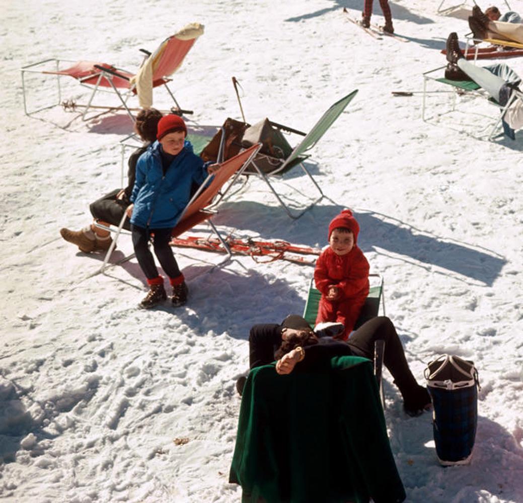 Vacances à Verbier : Des skieurs en vacances prennent le soleil au sommet d'une montagne enneigée à Verbier, 1964. Dans l'une des images les plus populaires et les plus emblématiques de Slim Aaron, des notes vives et colorées de rouge, de jaune, de