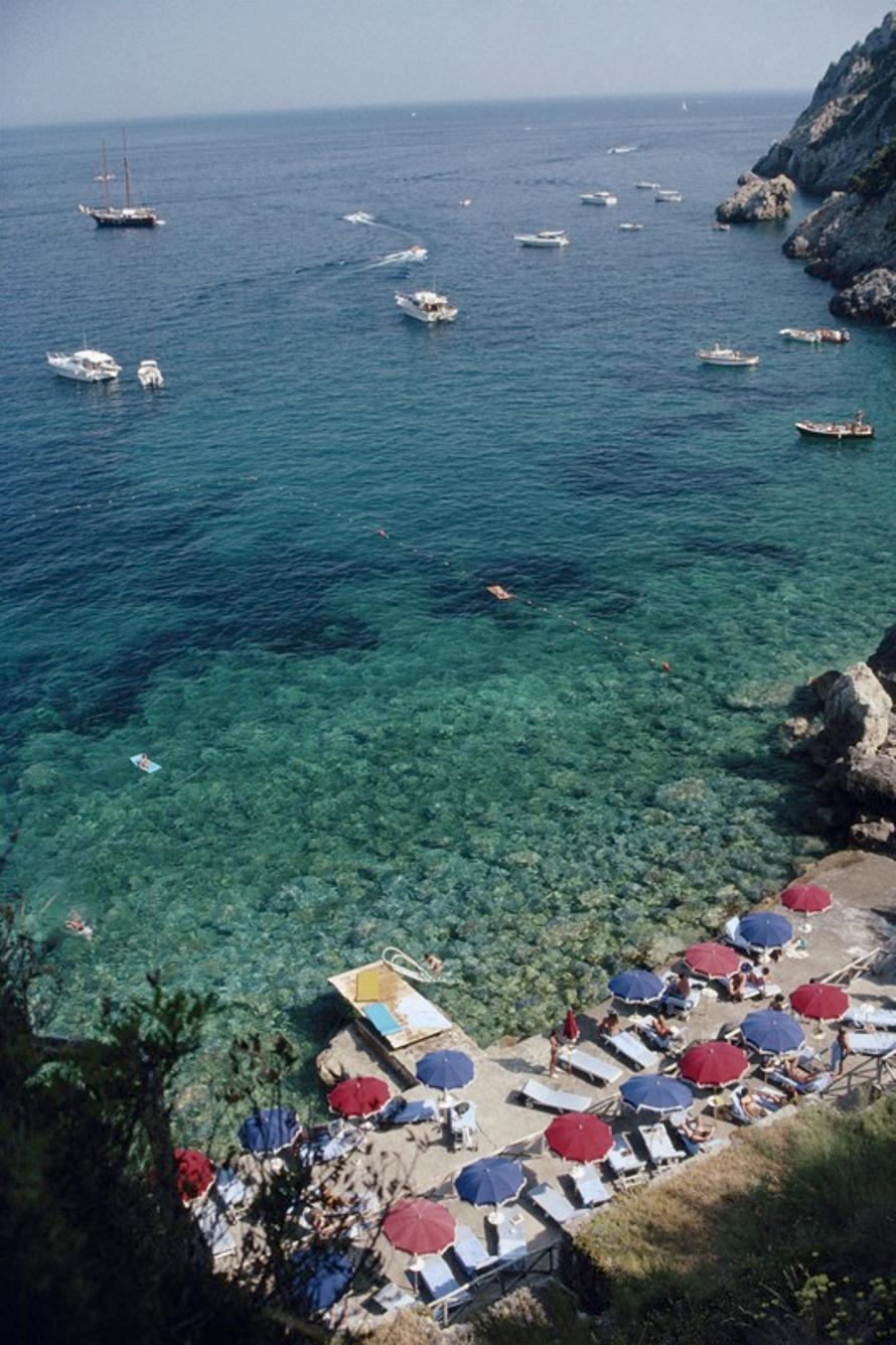 Blick von Il Pellicano 
1991
von Slim Aarons

Slim Aarons Limited Estate Edition

Luftaufnahme der Gewässer vor der Küste von Porto Ercole, Italien, im Juli 1991, mit Sonnenanbetern und Sonnenschirmen sowie Yachten und kleinen Booten. Das Bild wurde