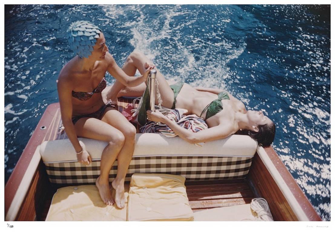 'Vuccino And Rava' Capri 1958

Slim Aarons Limited Edition Estate Stamped Print

Carla Vuccino, wearing a swimming cap, and a sunbathing Marina Rava, both wearing bikinis as they sit on the rear of a boat, on the waters off the coast of the island