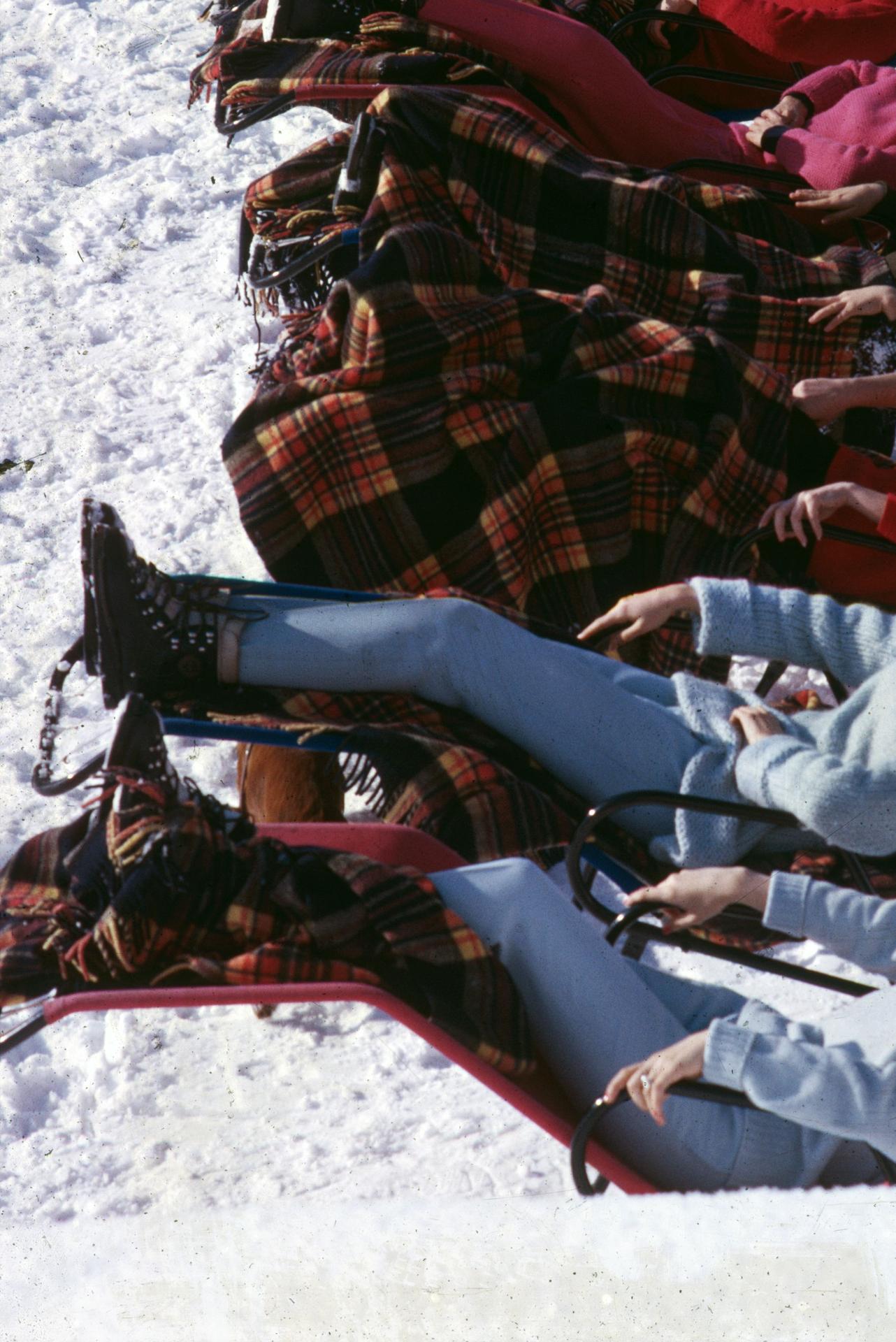 Esta fotografía de retrato de grupo de finales de la década de 1960, captada por el fotógrafo de sociedad Slim Aarons, muestra a mujeres jóvenes disfrutando de un relajante baño de sol en la nevada Gstaad. 

Se trata de una edición sellada y