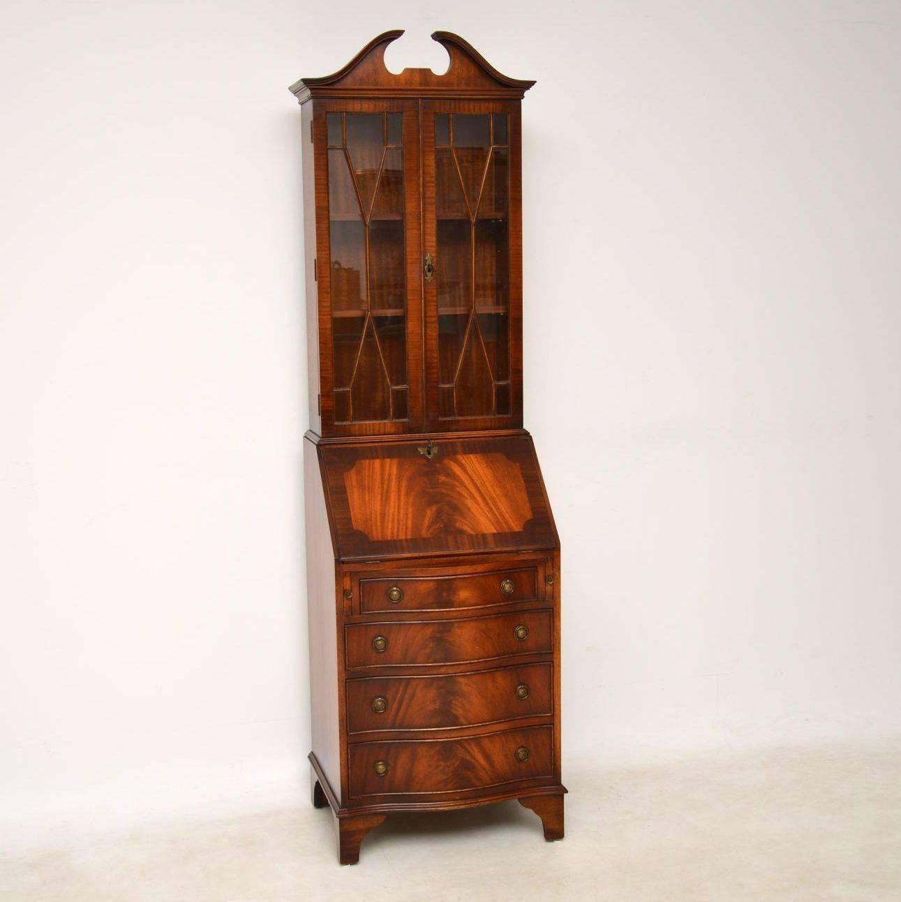 This flame mahogany bureau bookcase has lovely slim proportions and some great features. It's antique Georgian style, dating from around the 1950s period and is in excellent condition. The pediment is well shaped on top of astral-glazed doors with