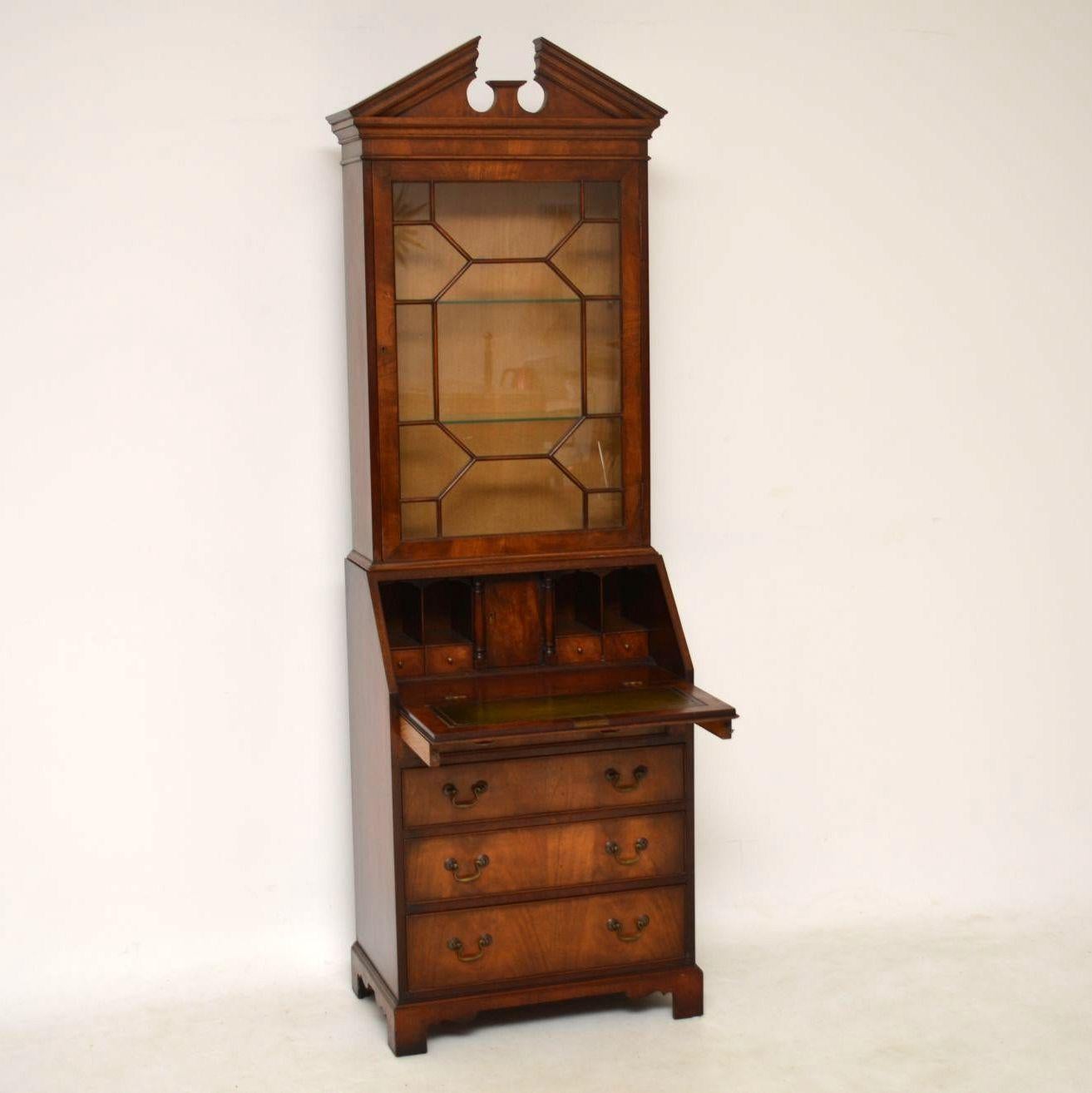 Slim antique Georgian style mahogany bureau bookcase in very good condition and dating from circa 1950s period. It has a sharp double pediment on the top and single astral glazed door below with two glass shelves inside. The fall front is flame