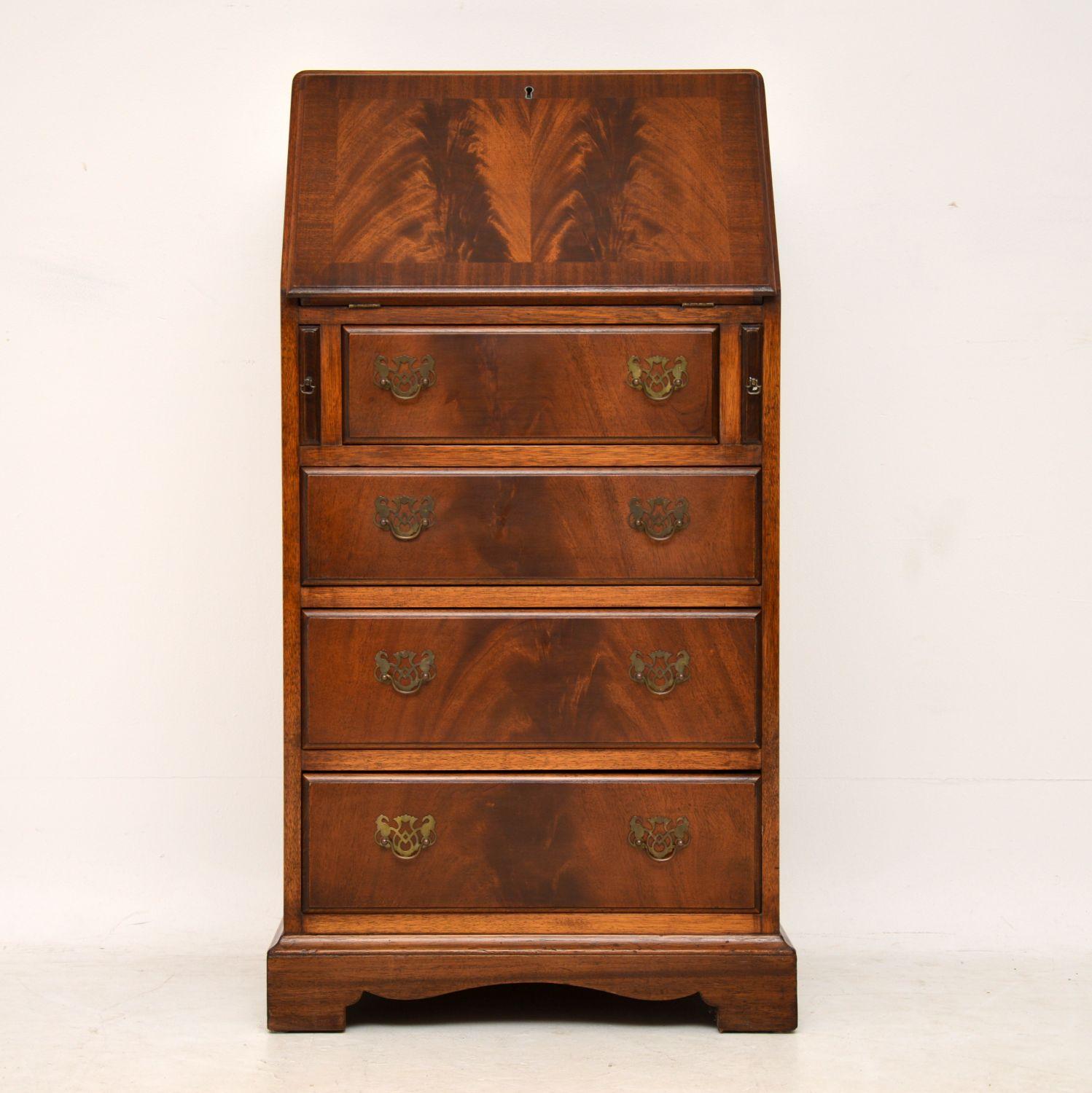 Slim proportioned antique flame mahogany bureau dating from the 1930s period and in excellent condition having just been French polished. It has a pull down flap revealing the original tooled leather writing surface with compartments and a small