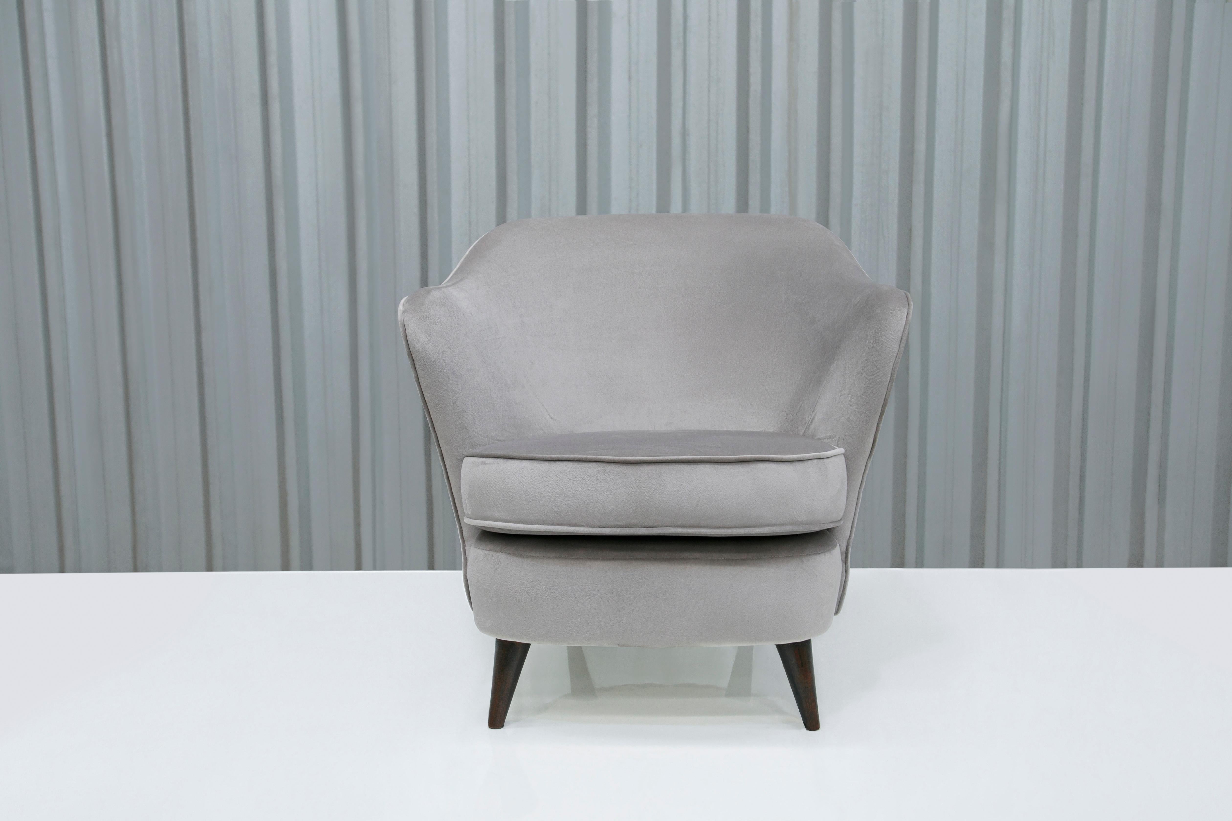 This slim armchair is made with a wooden frame and a soft gray fabric. The legs of the chair are slim, which is a common theme in Brazilian modern armchairs. The cushions are super soft and make the chair very comfortable. This chair is very old but