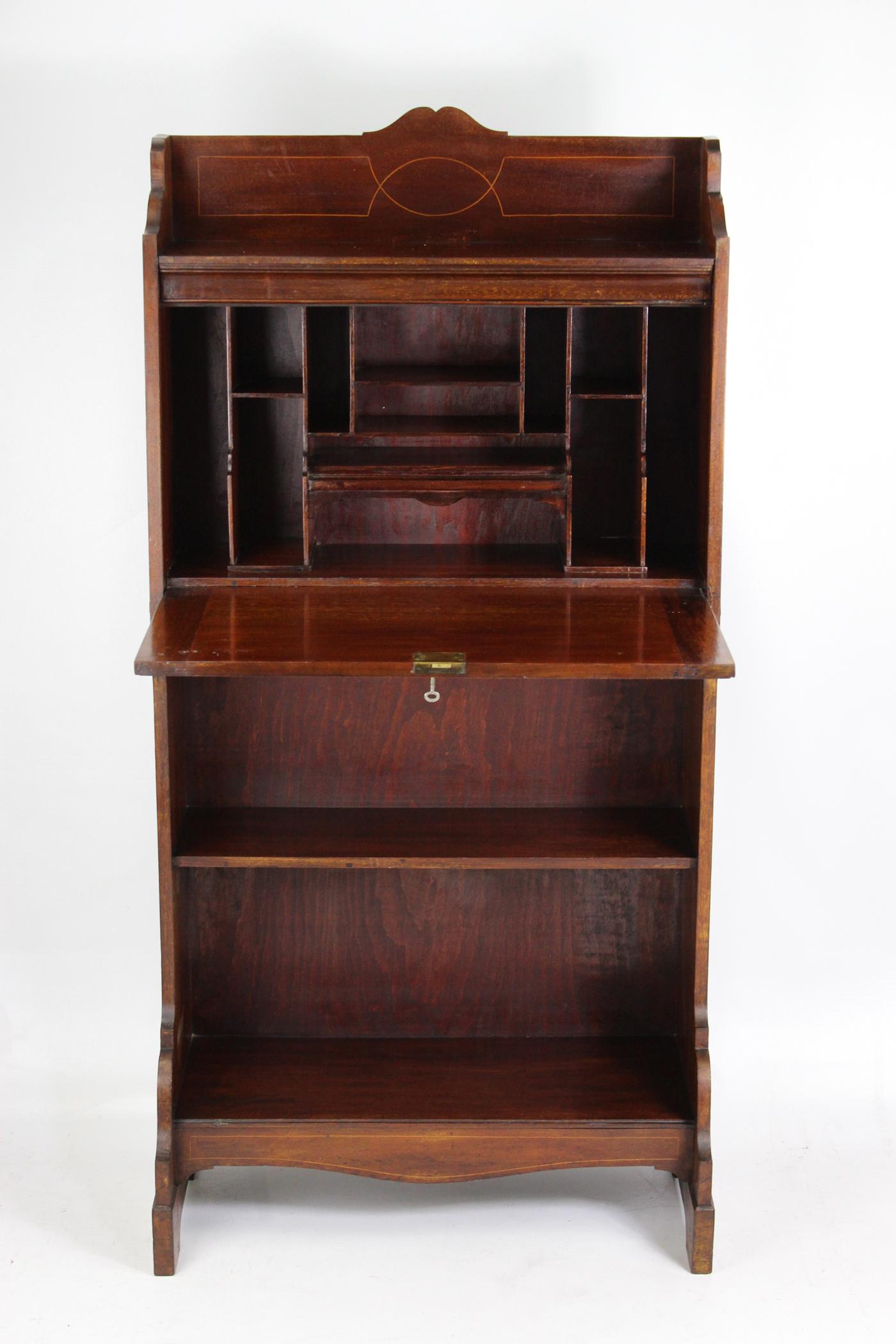A handsome small antique Edwardian Arts & Crafts bureau in mahogany with satinwood inlay dating from circa 1905. With good color and in good condition, it has a shaped gallery top above a fall above and an open bookshelf and stands on shaped bracket