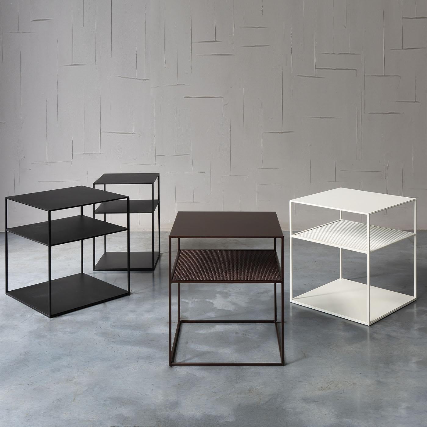 Leichtigkeit und Strenge bestimmen diesen Couchtisch, der nach minimalistischen Designprinzipien entworfen wurde. Die aus schwarzem Kupfer gefertigte und in einem raffinierten Sand-Finish angebotene Struktur besteht aus einem Aufsatz, einer Ablage