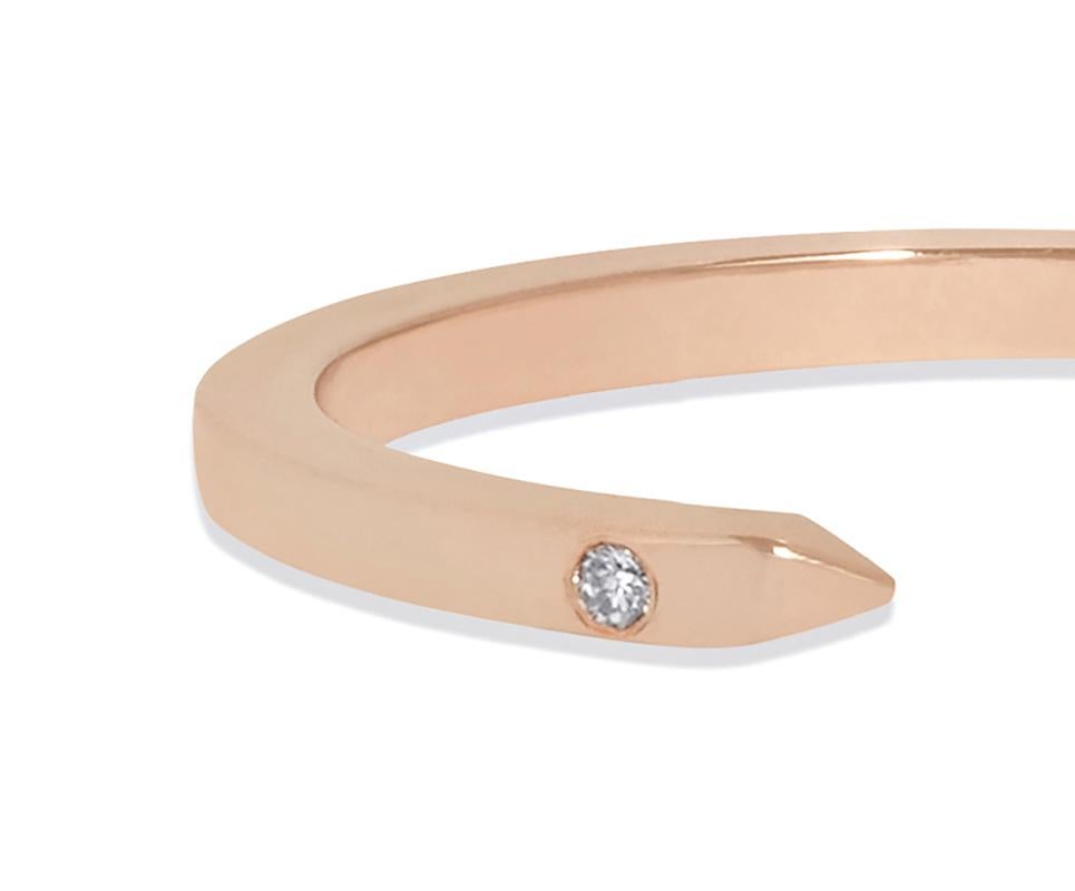 Understated yet edgy, this slim open ring in 18-carat rose gold is accented with two sparkling white diamonds.  Equally at home alone on the finger or stacked with other gold bands.  Total carat weight .016 white diamonds. In stock in UK size K