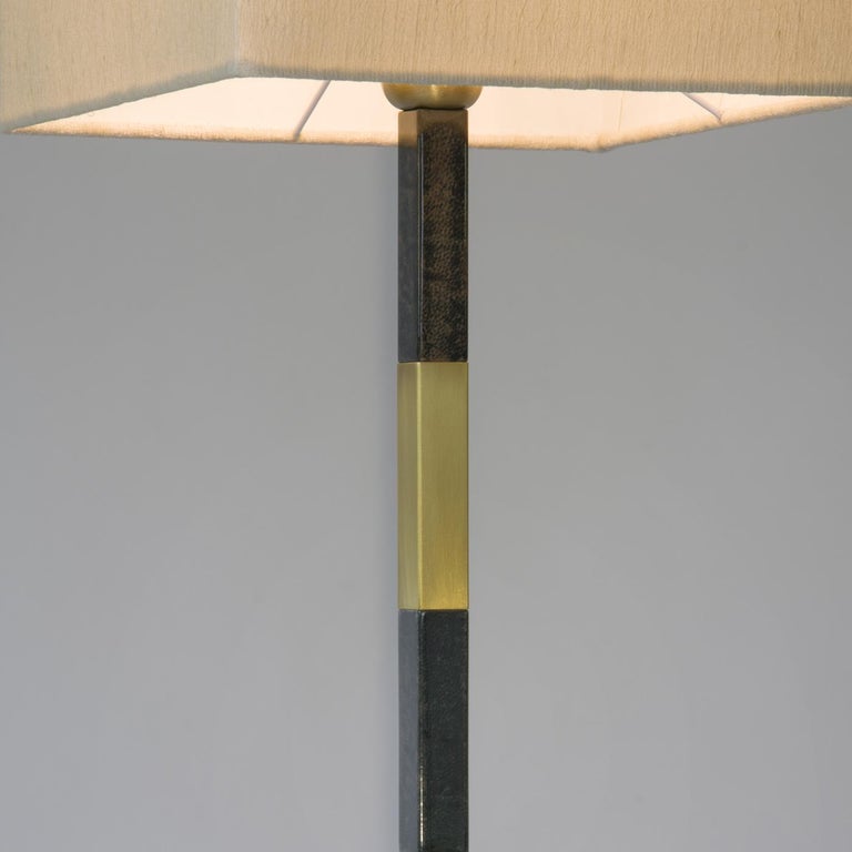 Characterized by a clean and elegant design, the stylish slim table lamp features a base in brushed brass and attractive detail in tobacco colored parchment. The sleek base combines with a neutral tone fabric lampshade to provide soft illumination