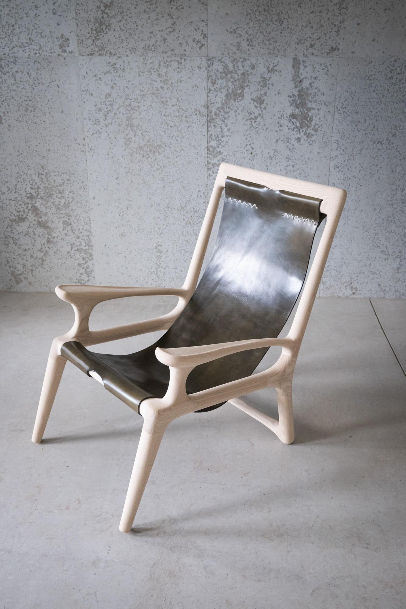 Dieser Stuhl ist genau wie unser Classic Sling Stuhl, mit einer Ausnahme: Die Armlehnen sind mit den Rückenlehnen verbunden. Dieses Angebot umfasst einen Stuhl.

Dieser preisgekrönte Sling-Stuhl aus Leder und Holz ist das erste Stück, das Fernweh