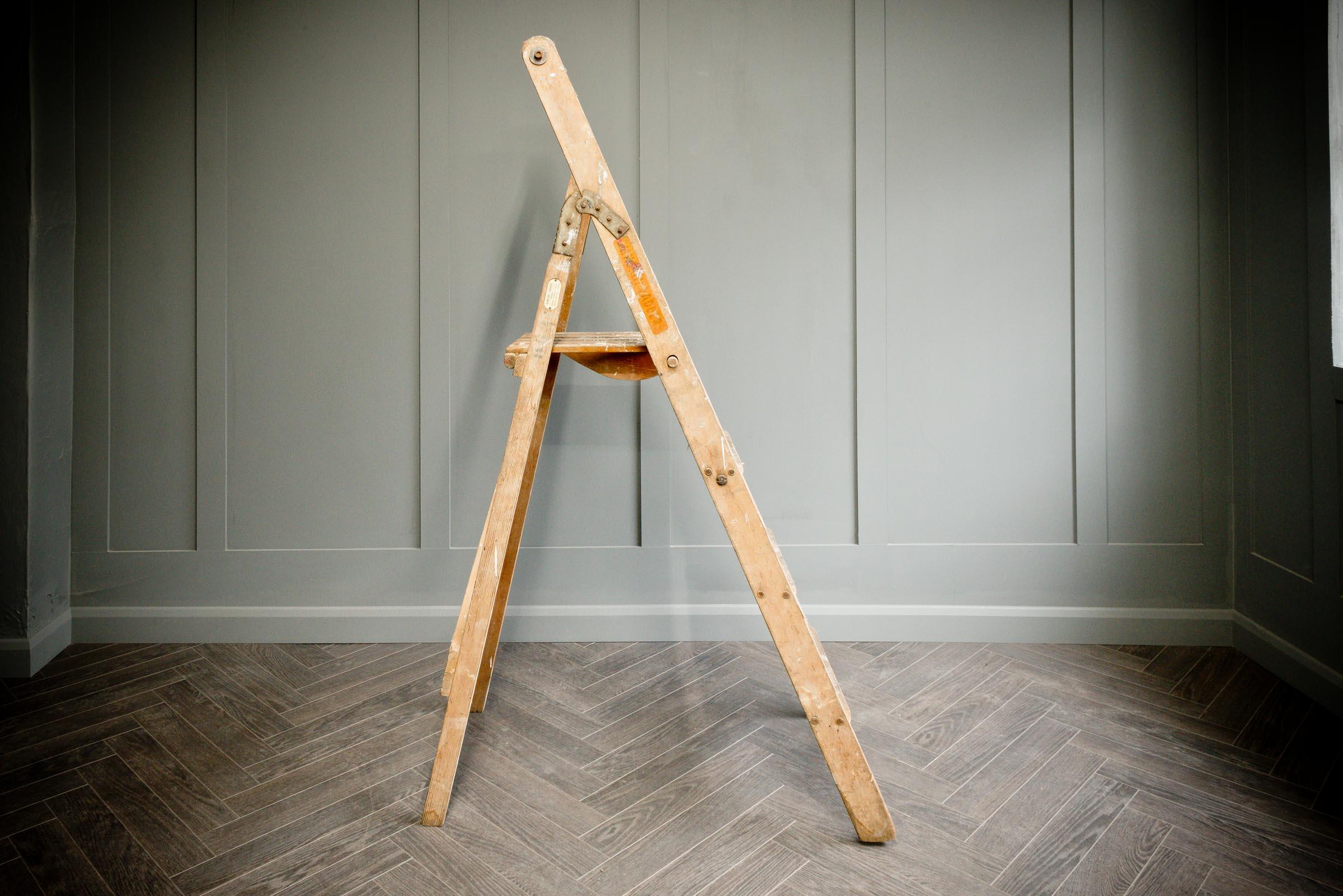 An original wooden Slingsby step ladder in medium size, consists of three steps and the fourth tray top. The ladder closes by two metal hinges either side of the ladder. The ladder has original paint marks consistent with age and use.