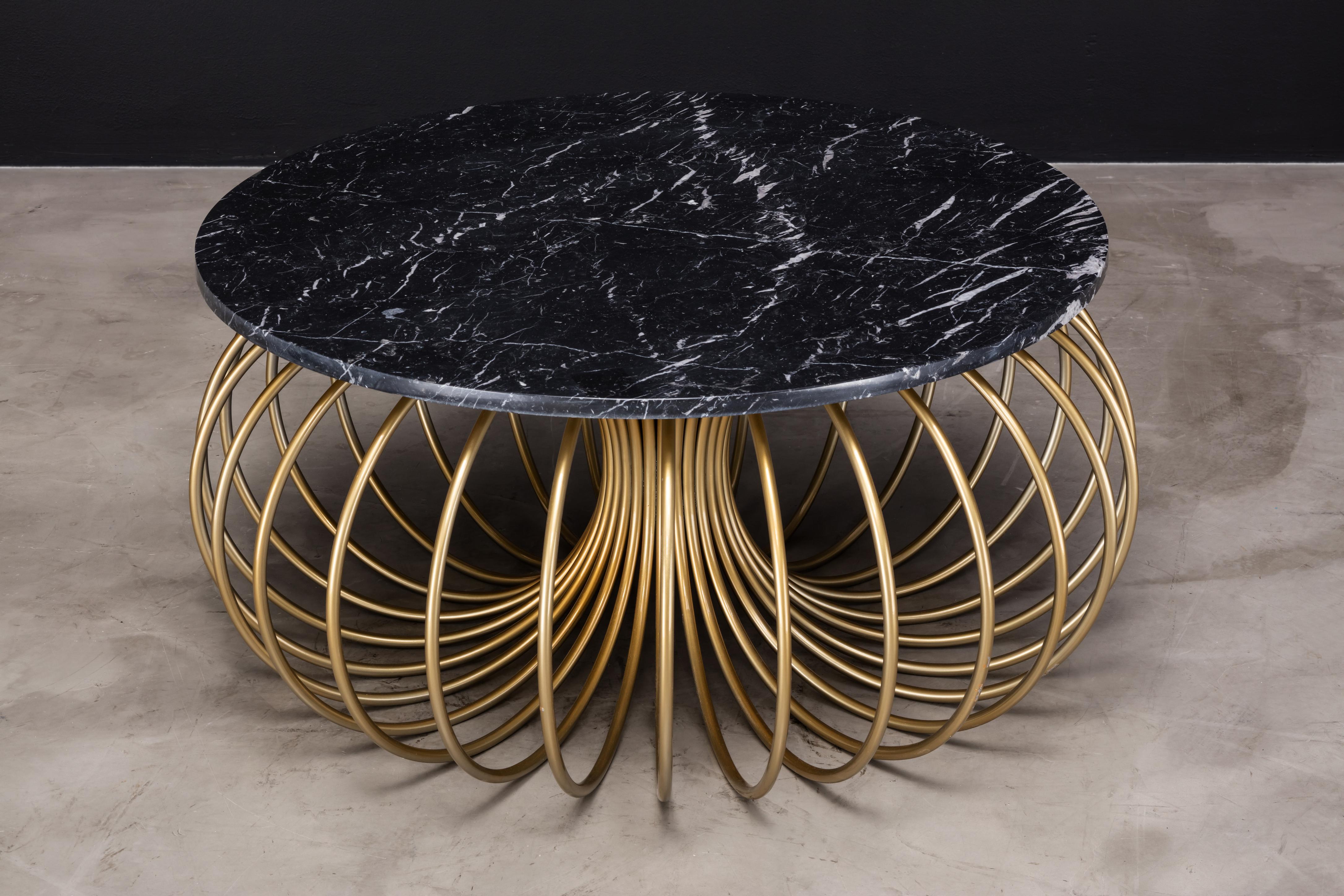 The Slink coffee table is a modern cocktail table made of powder-coated metal with a Nero Marquina marble top. The symmetrical and circular base set this beautiful piece apart from the ordinary. This is a showroom sample in new condition at a