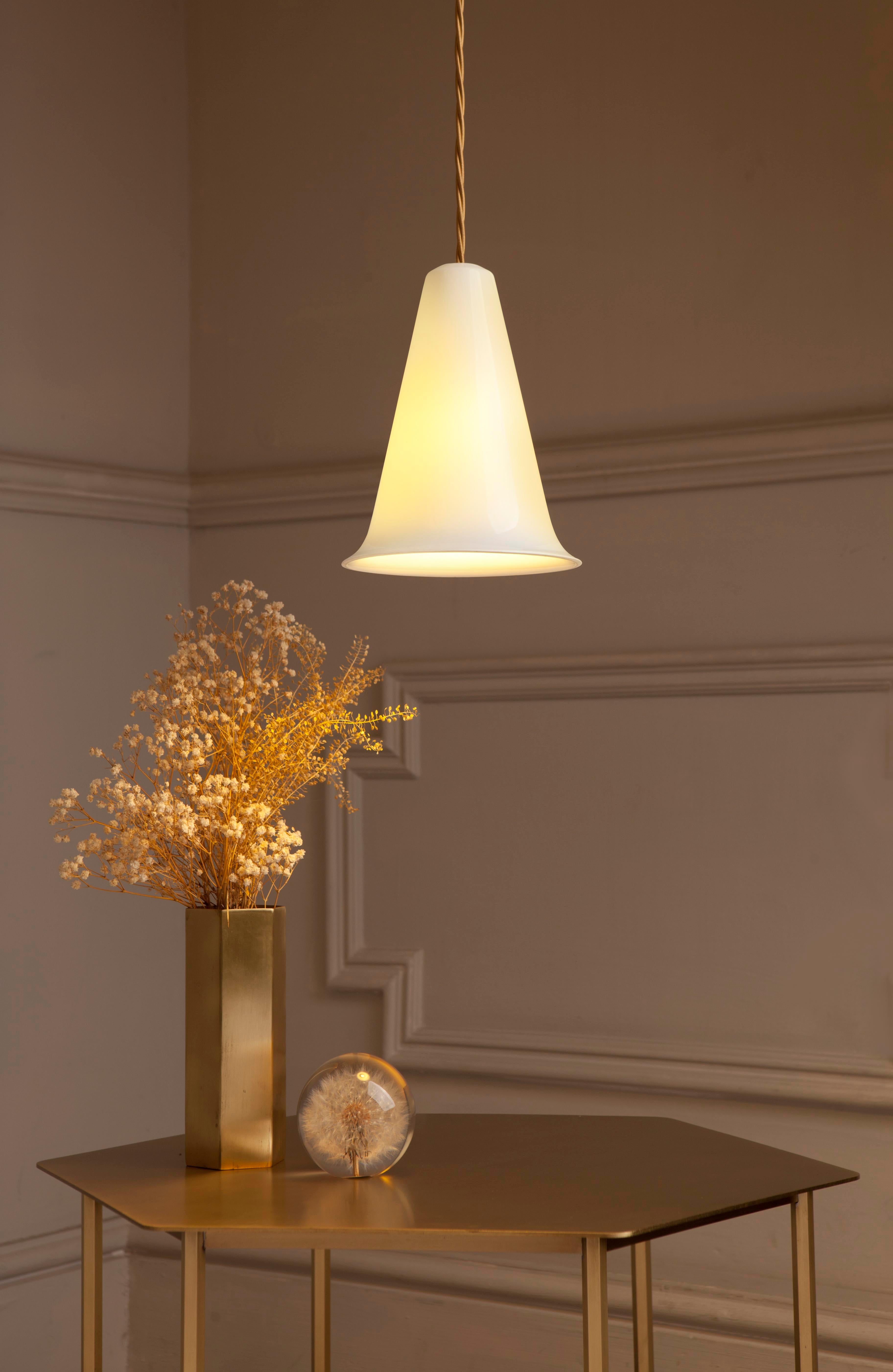 The bone china ceramic lampshades feature a simple and soft silhouette, their slightly translucent materiality reveal a warm light. The pendants are slip cast, fired and coated in a clear glaze. They feature golden twisted three core cords and brass