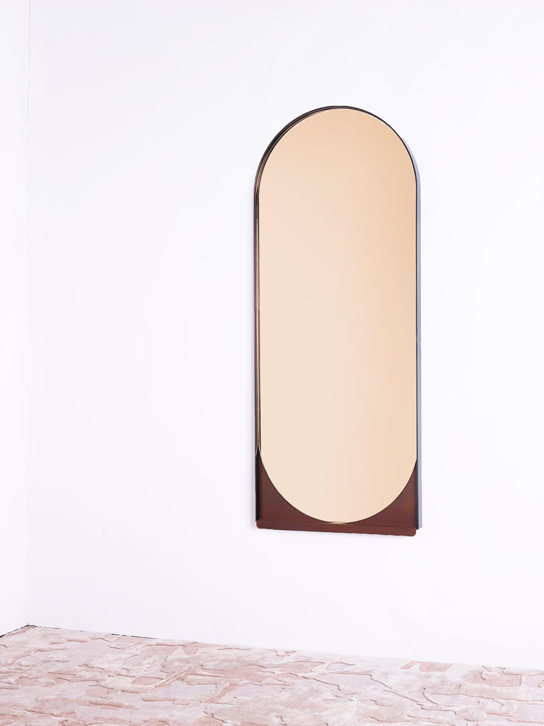 Simplicity is key to the slip mirror, whose thin blackened stainless steel frame delicately holds an oblong mirror. A contrasting red oxide shelf slips out from below, hinting at hidden layers beneath.
 