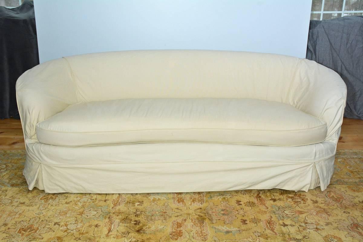 Beautiful 1950s curved sofa with alluring low swung lines. Original velvet on sofa has yellowed and also lacking the cover for the seat cushion,  Slip cover has some stain in the back.  Sofa is ready for new upholstery or new slip cover at an