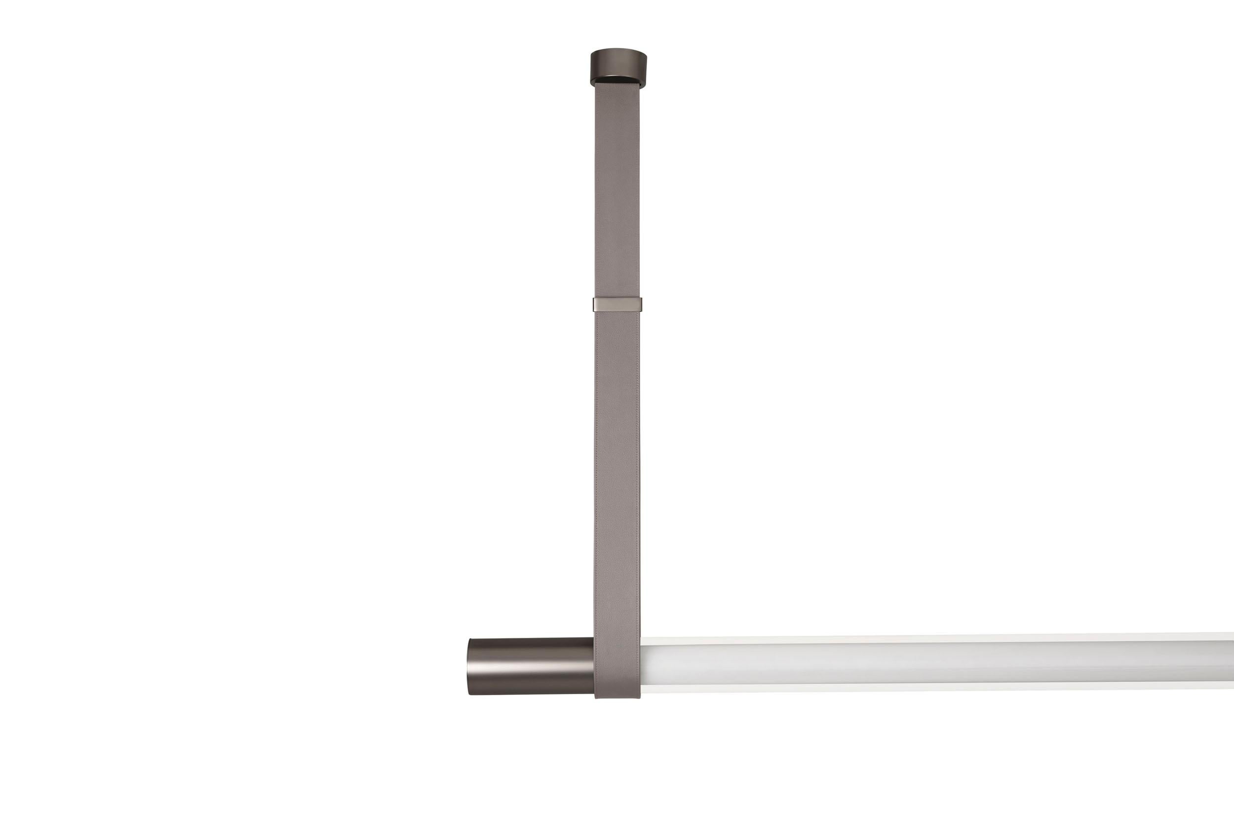 Lampada a sospensione a luce diffusa. Struttura costituita da un diffusore tubolare in vetro borosilicato, con
finitura opalina, sospeso mediante cinte in pelle cablate nelle varianti di colore: polvere, antracite, toupe.
Al suo interno un sistema