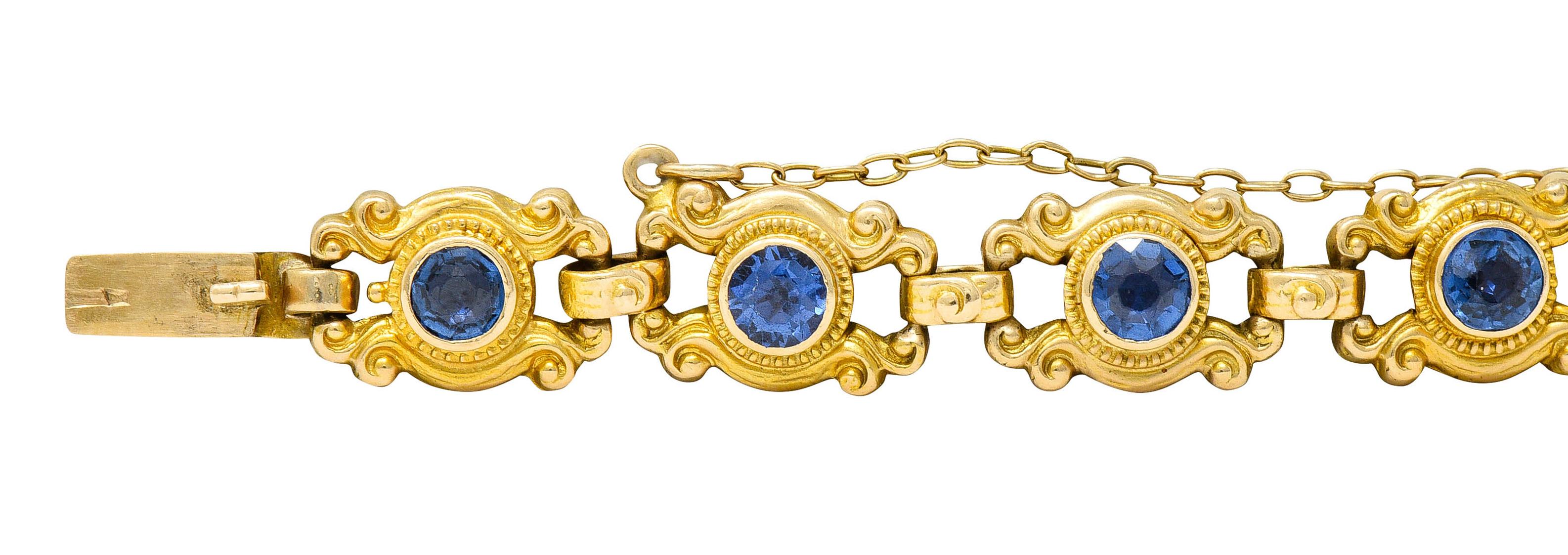 Bracelet is comprised of scrolling whiplash links accented by milgrain

Each centers a bezel set and round cut sapphire

Weighing in total approximately 4.50 carats - very well matched violetish blue color

Completed by a concealed clasp and chain