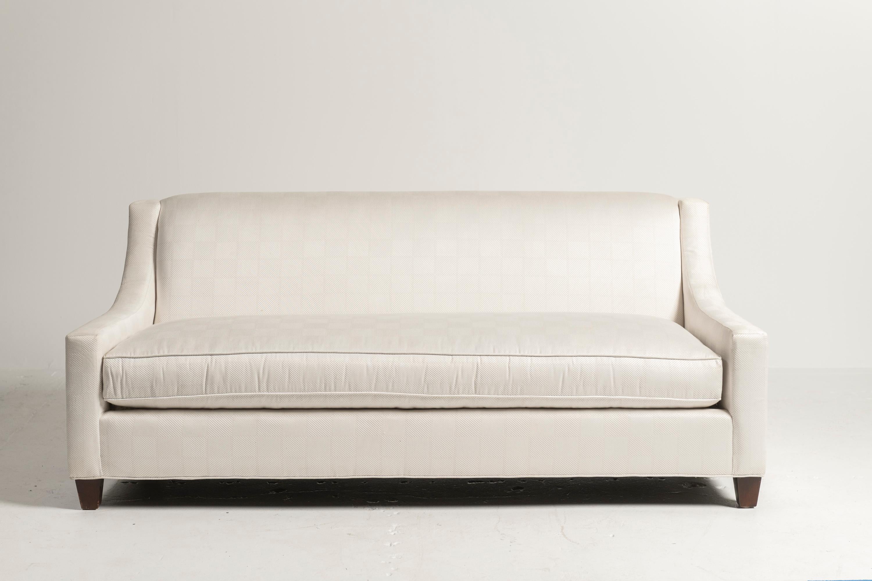 Canapé confortable à accoudoir incliné avec un seul coussin et des pieds en forme de blocs fabriqués par Baker Furniture. Le rembourrage en peluche offre un soutien exceptionnel, ce qui le rend idéal pour se détendre ou recevoir. Son design élégant