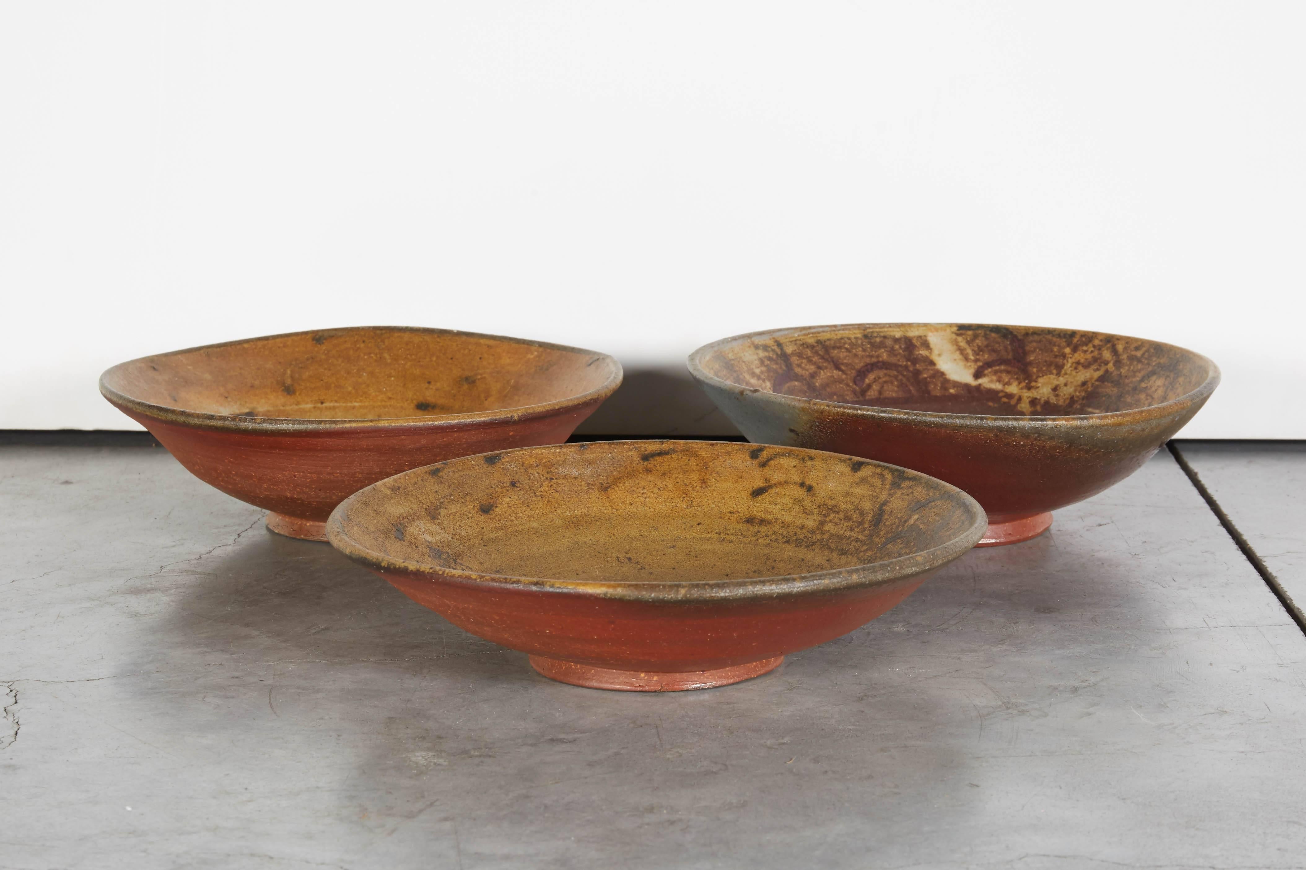 Three 20th century handmade Japanese Bizen ware bowls. These pieces were slow fired for 10 days or more in the traditional kilns of the Bizen province of Japan and show the characteristic traces of molten ash on the red clay bodies. Each piece is