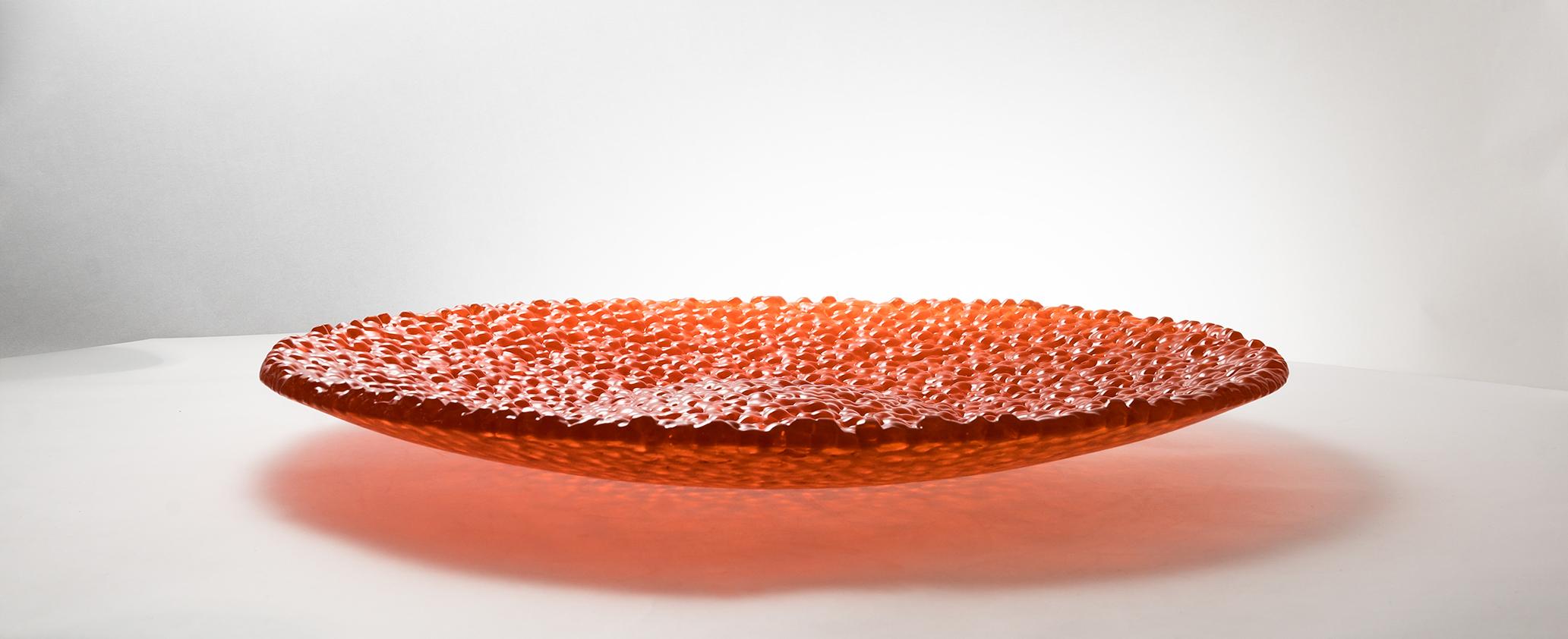 SLU platter.
▪Large serving plates edition.
▪Bold transparent orange glass.
▪Plates body is made of hundreds of small balls, fused with one another.
▪Basic geometrical shape, complex color and structure mix.
▪Made only with the usage of recycled