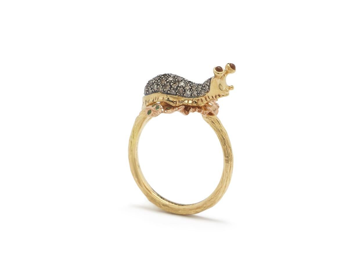 A sweet slug, embellished with brown diamonds, appears to crawl along this stackable ring. The ring is designed in 18k yellow gold and set with 18k rose gold leaves that glisten with tsavorites, while the slug is fashioned in 18k yellow gold and