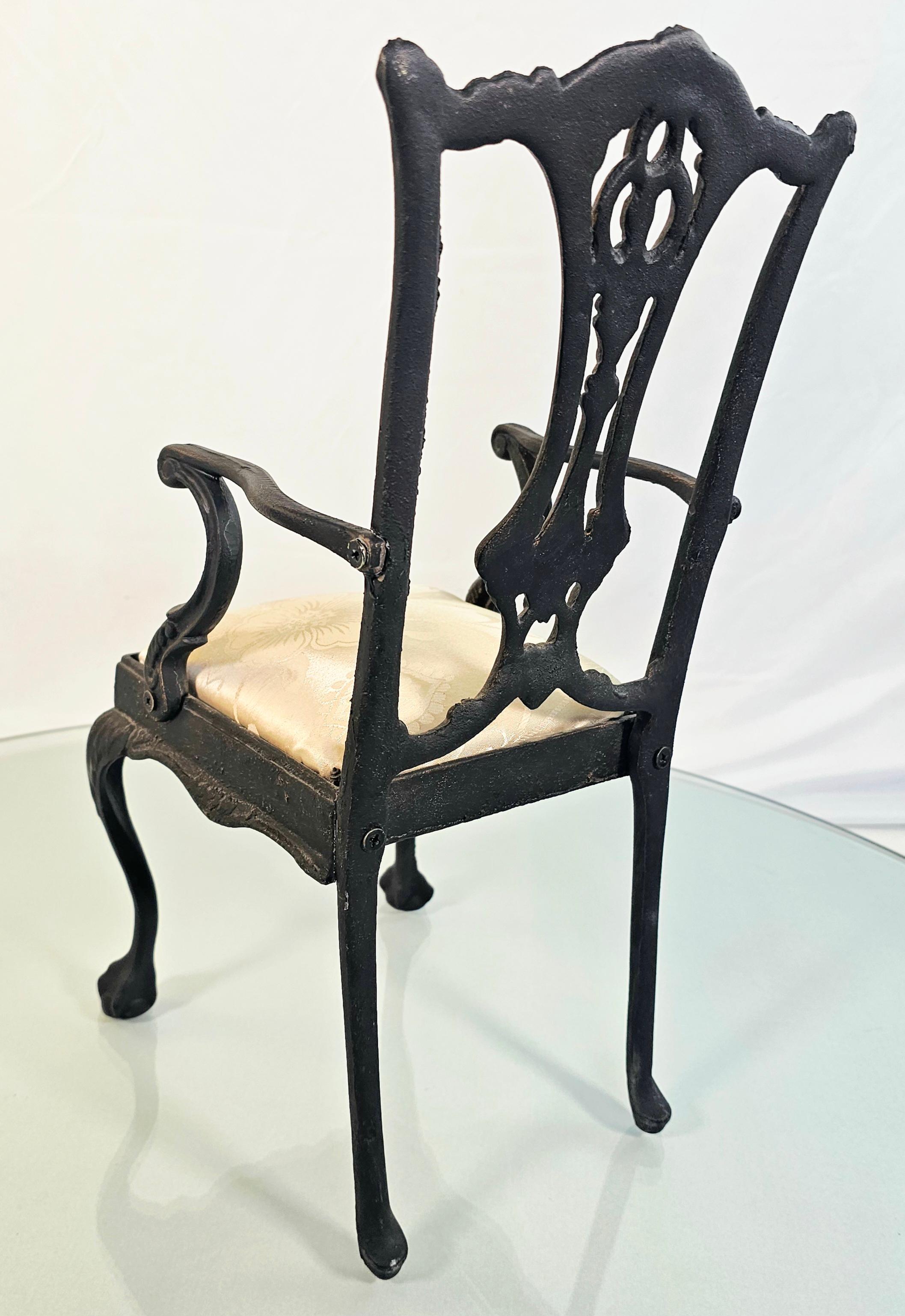 This small cast iron armchair is a unique addition to any collection. It stands at 17 inches tall and was used as a salesman's sample. The armchair is made from durable cast iron and has a sturdy seat and backrest. The object type is an armchair and