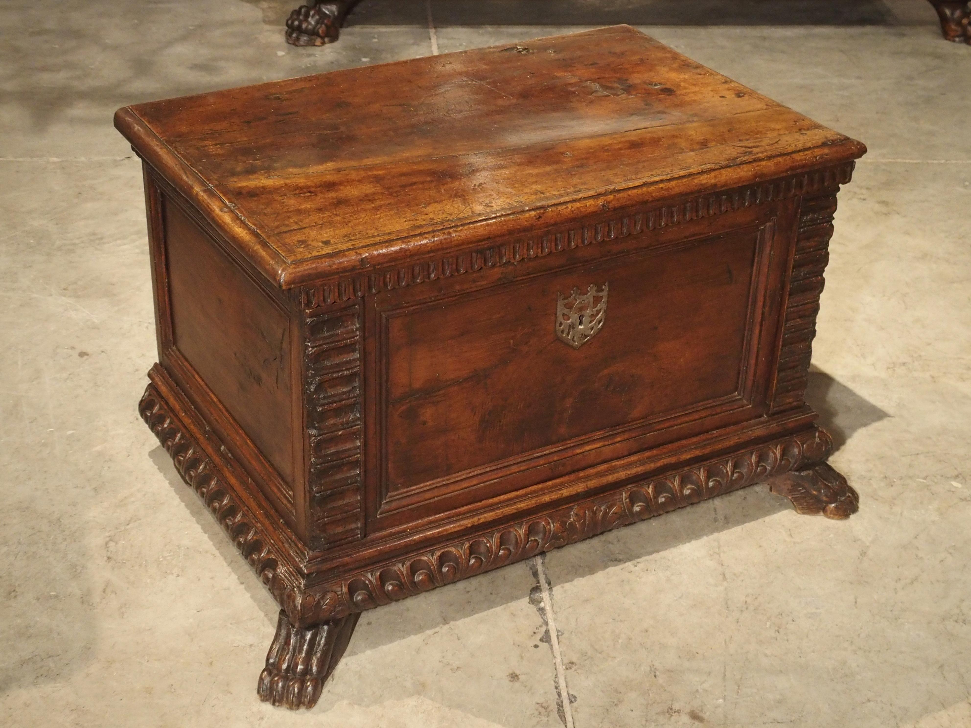 This small walnut wood trunk from Italy is largely made with elements dating to the 1600s. The top, front and sides have plain panels outlined with moldings. The decorative motifs are triglyphs, scoops, gadrooned lobes and acanthus leaves. The feet