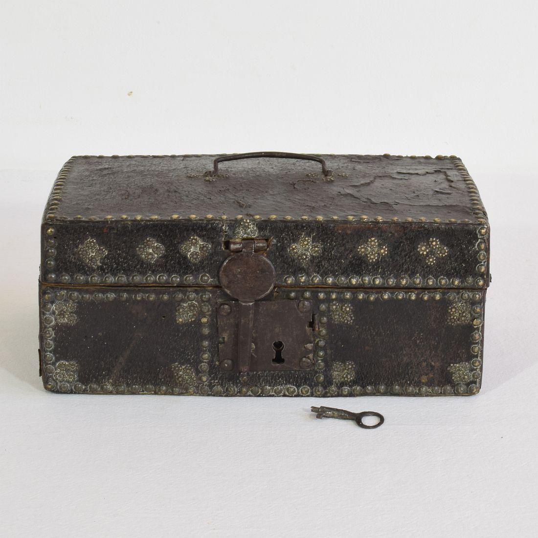 Extremely old box that is covered with leather and decorated with iron and brass. 
Rare find with original and working key and lock,
France, circa 1600-1700
Weathered and some losses.
 