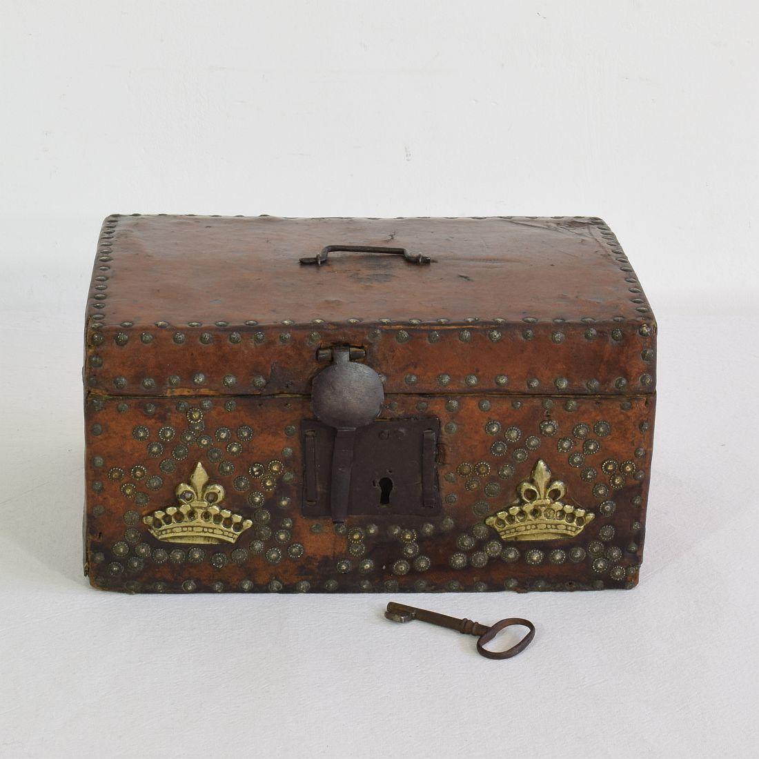 Extremely old box that is covered with leather and decorated with iron and brass. 
Rare find with original and working key and lock,
France, circa 1600-1700
Weathered and some losses.