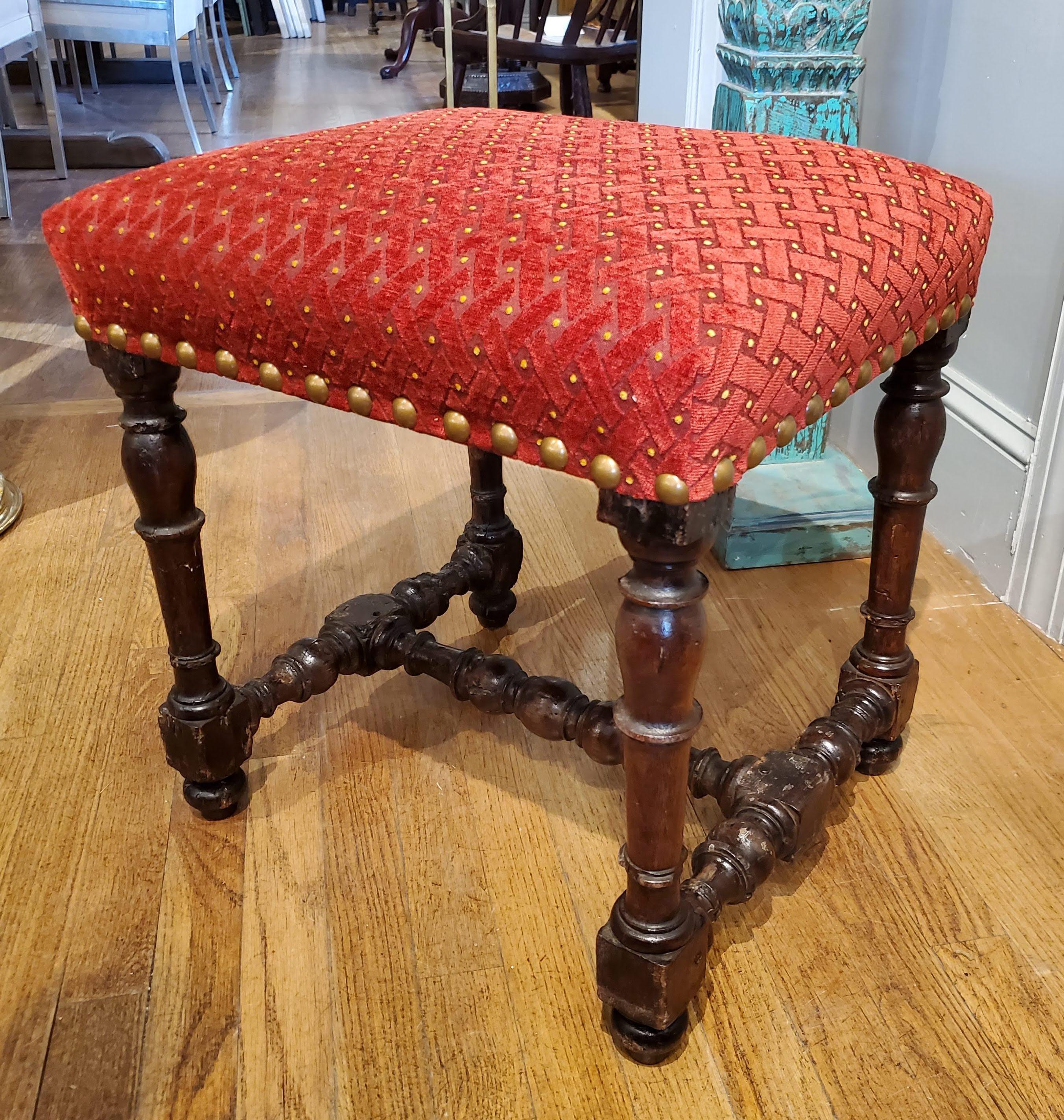 This small mid-17th century Louis XIV stool will be a beautiful additional to your sitting room. Made of deeply patinated walnut with turned legs and stretchers. Recently reupholstered in a stunning textured red chenille that has gold accent dots.